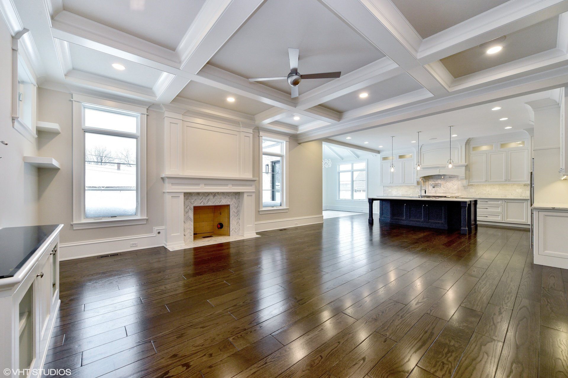 An empty living room with hardwood floors and a ceiling fan.
