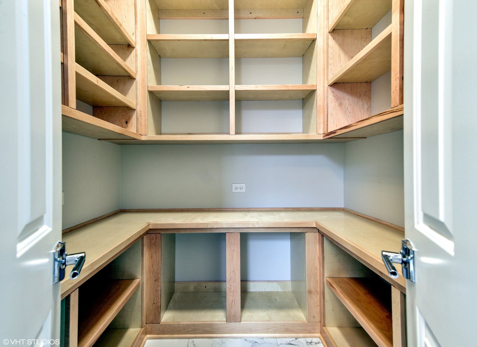 An empty pantry with wooden shelves and a white door