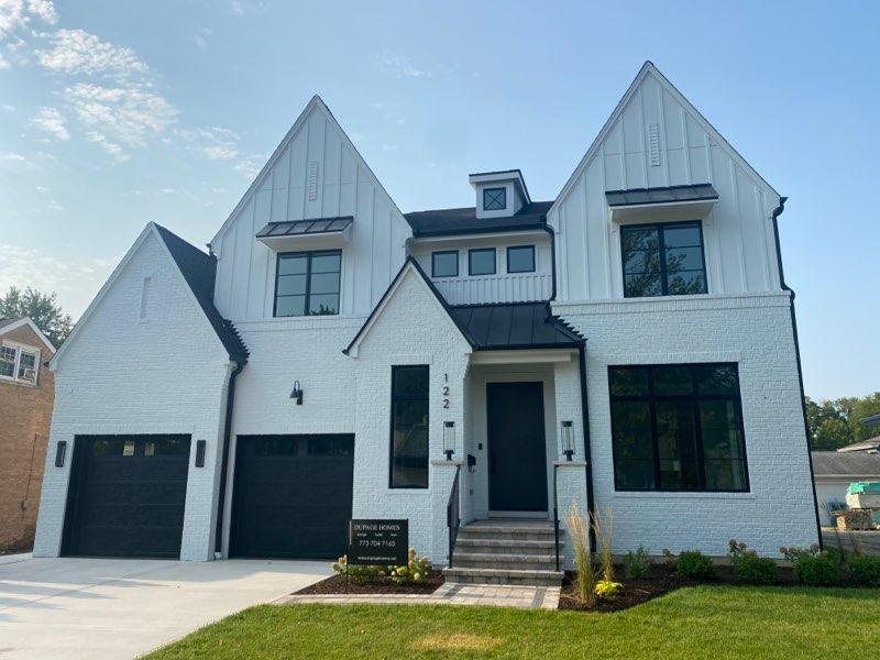 A large white house with black garage doors and windows.