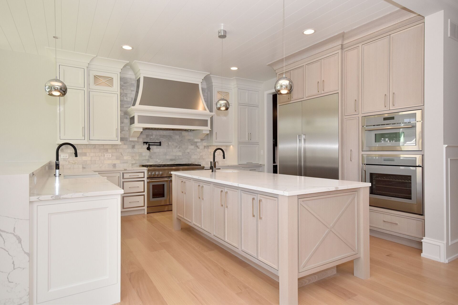A kitchen with white cabinets , stainless steel appliances , and a large island.
