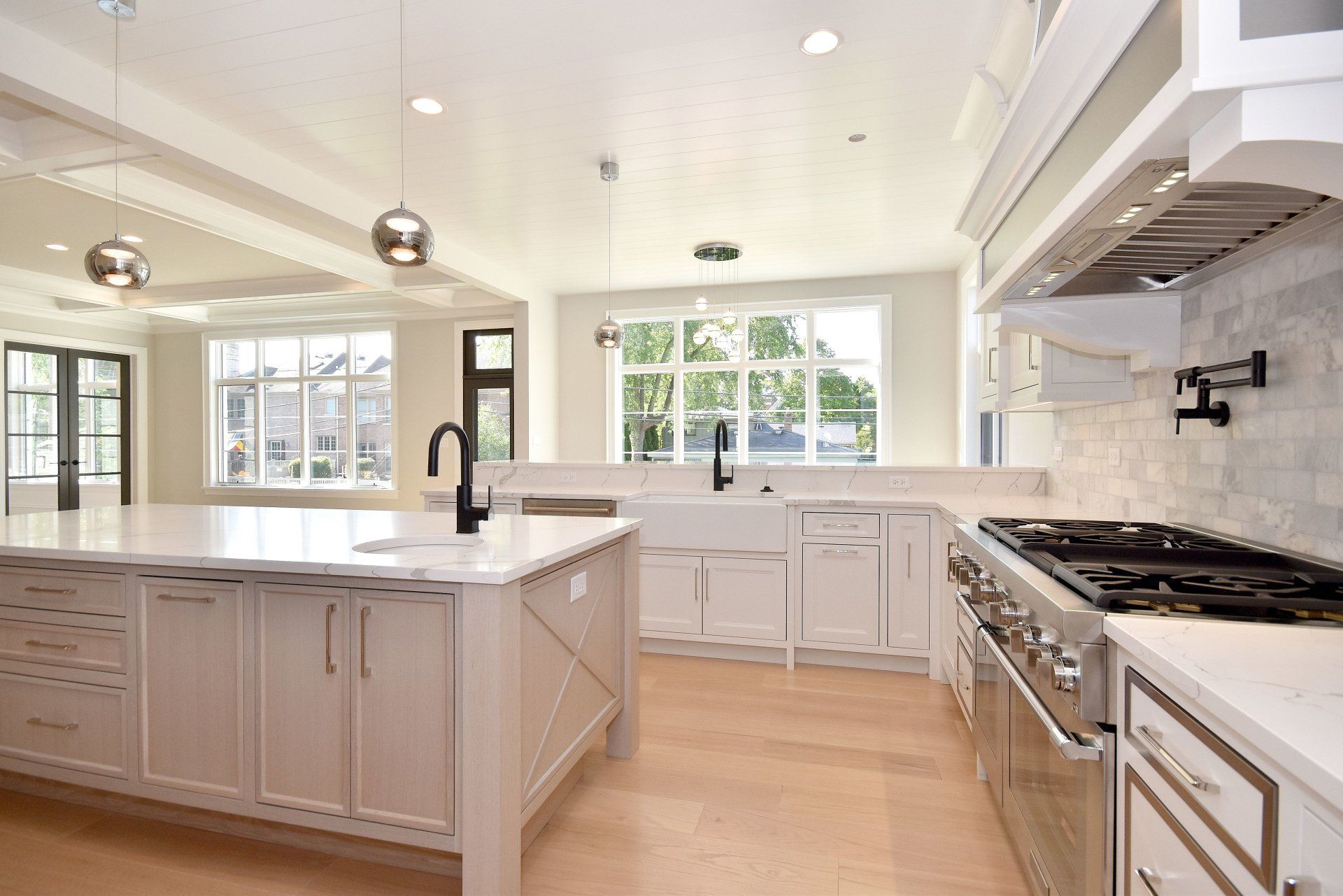 A kitchen with white cabinets , stainless steel appliances and a large island.