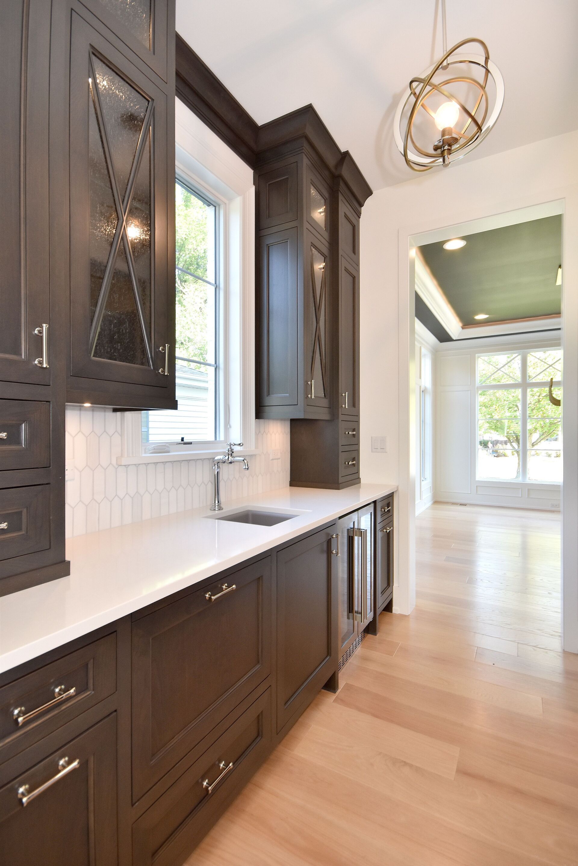 A kitchen with dark wood cabinets and white counter tops.