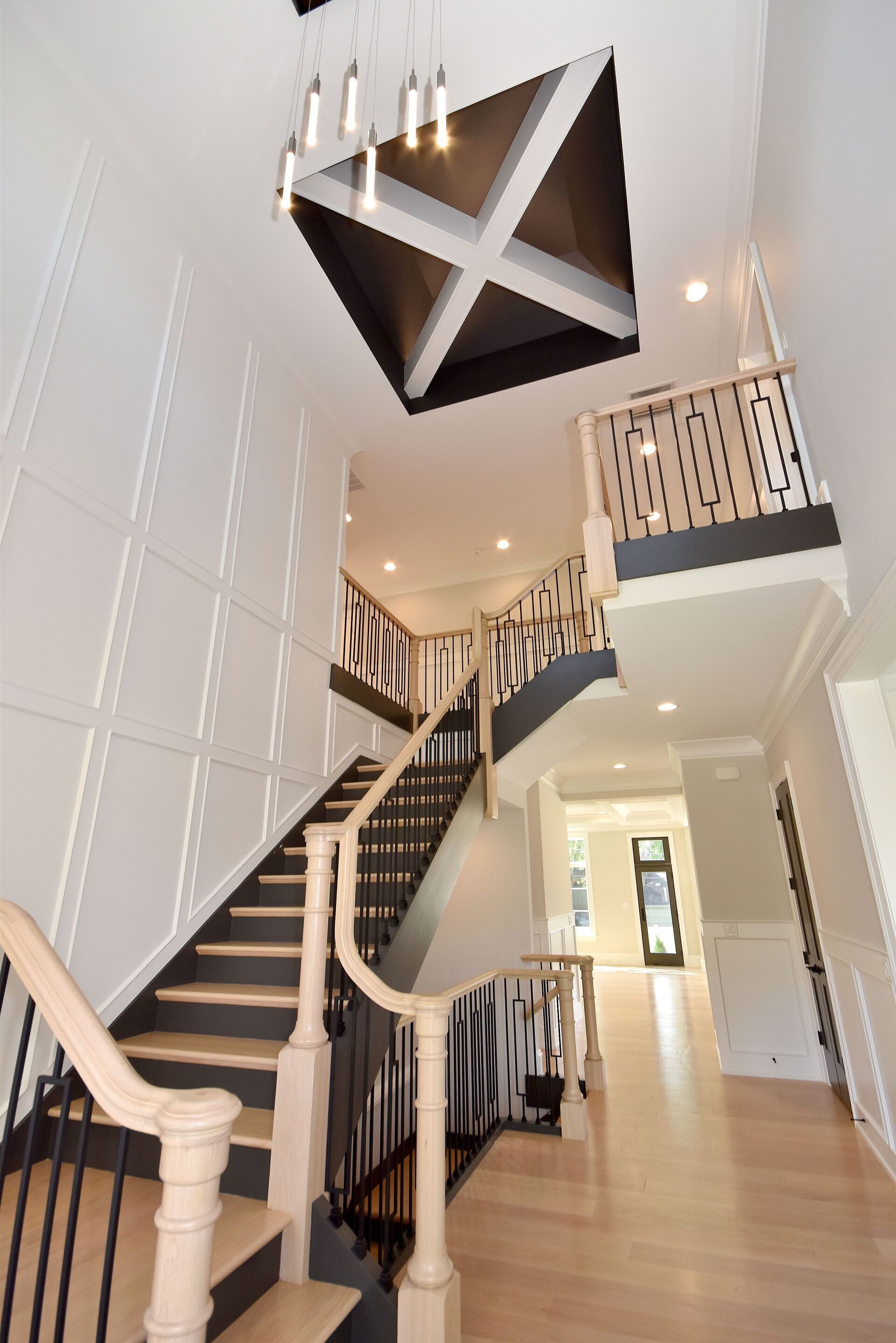 A staircase in a house with a chandelier hanging from the ceiling