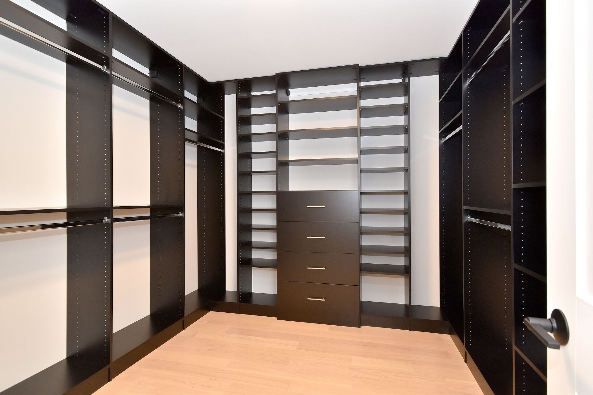 A walk in closet with lots of shelves and drawers