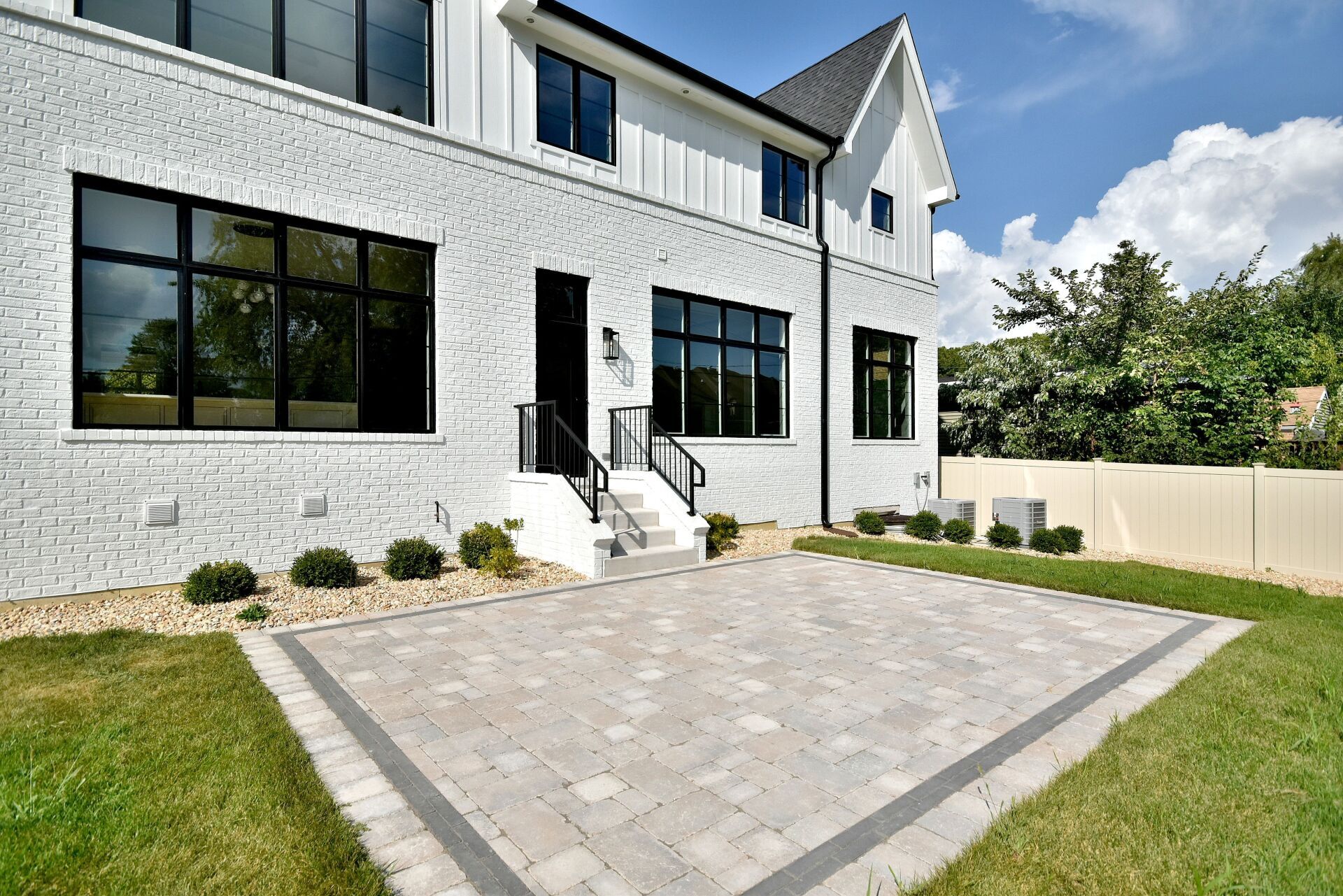 A large white brick house with a patio in front of it.