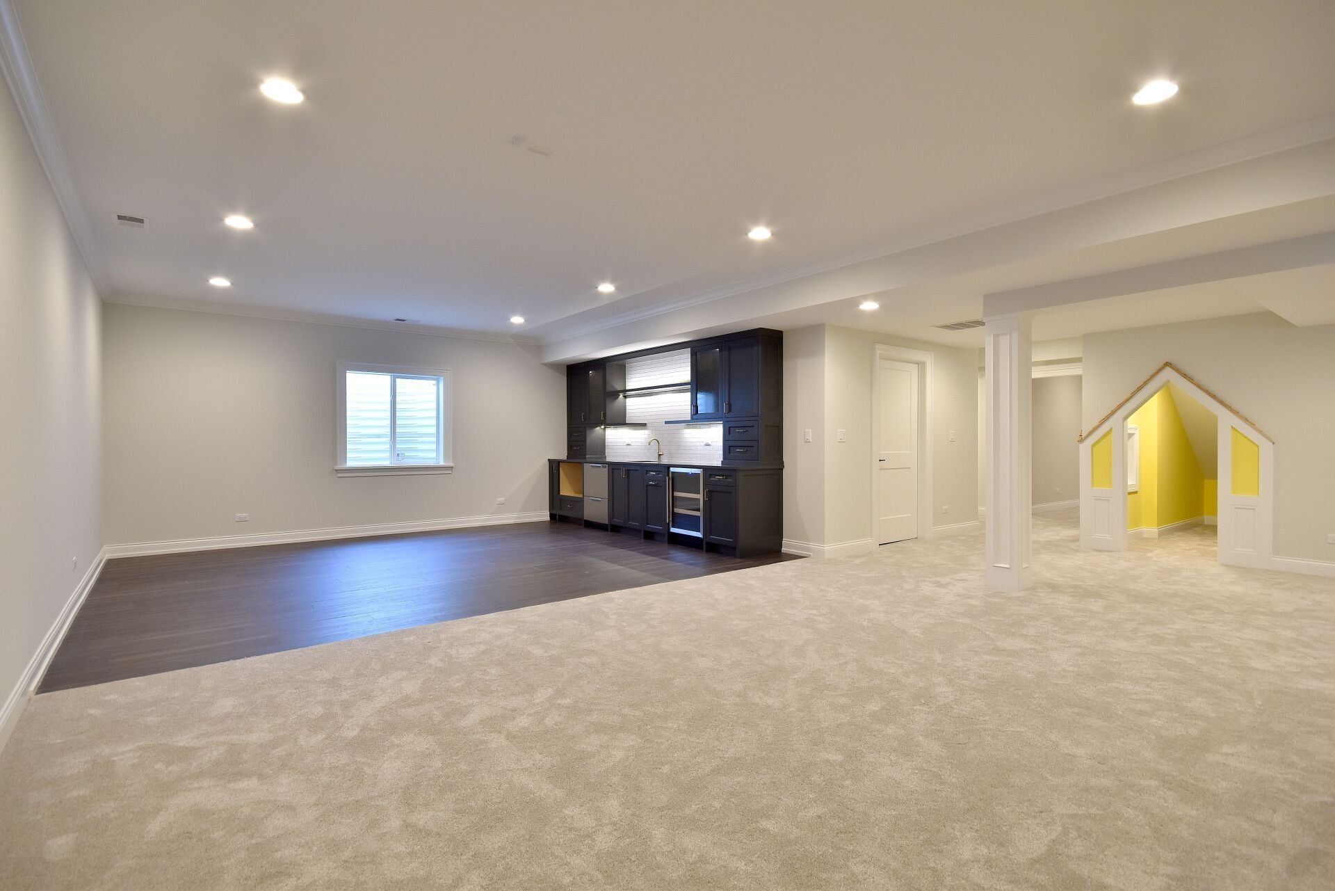 An empty basement with a carpeted floor and a window.