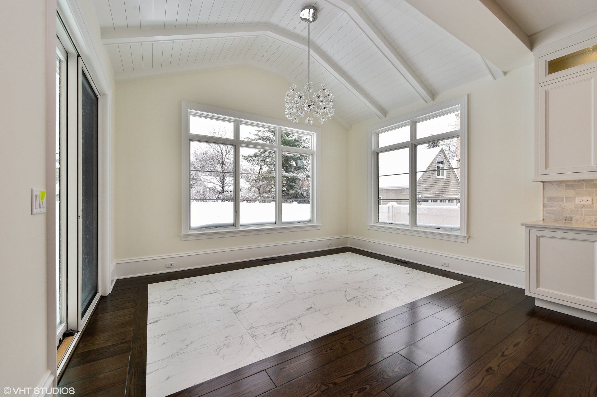 An empty room with a vaulted ceiling and lots of windows
