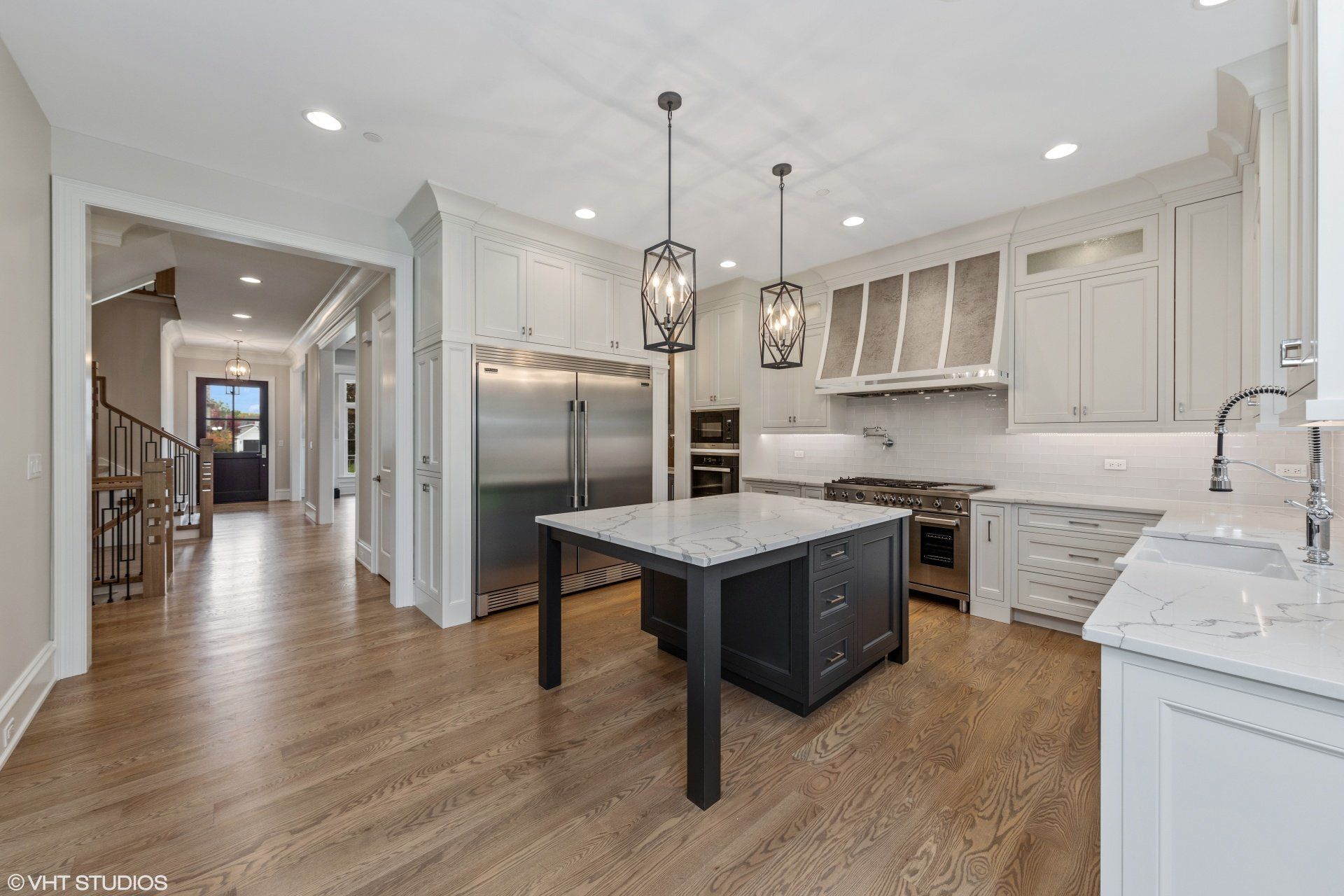 A kitchen with white cabinets and stainless steel appliances and a large island.