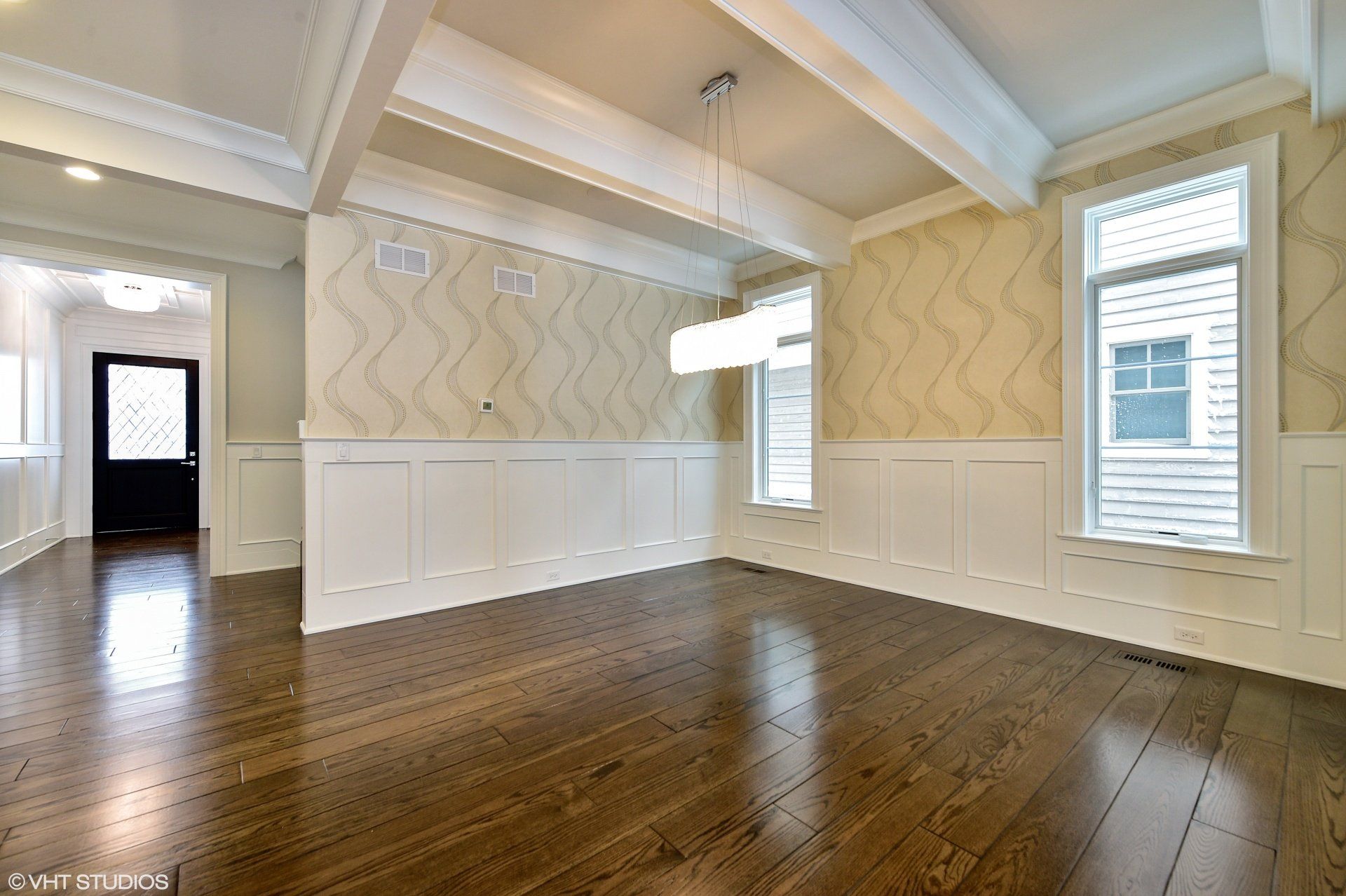 An empty dining room with hardwood floors and white trim