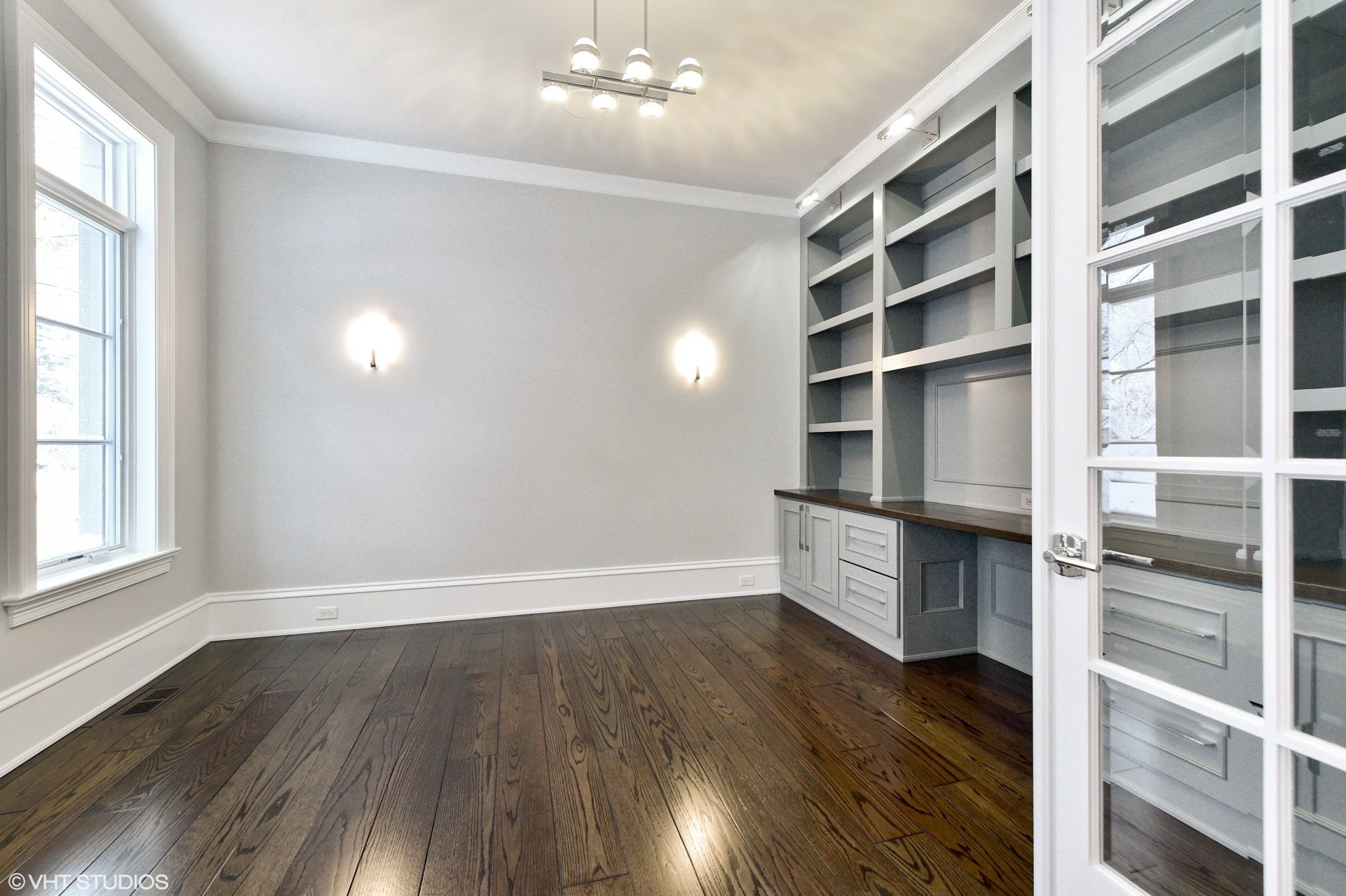 An empty room with hardwood floors and white cabinets
