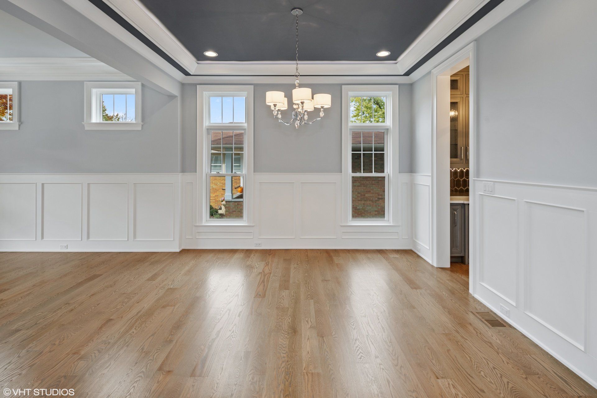 An empty dining room with hardwood floors and a chandelier.