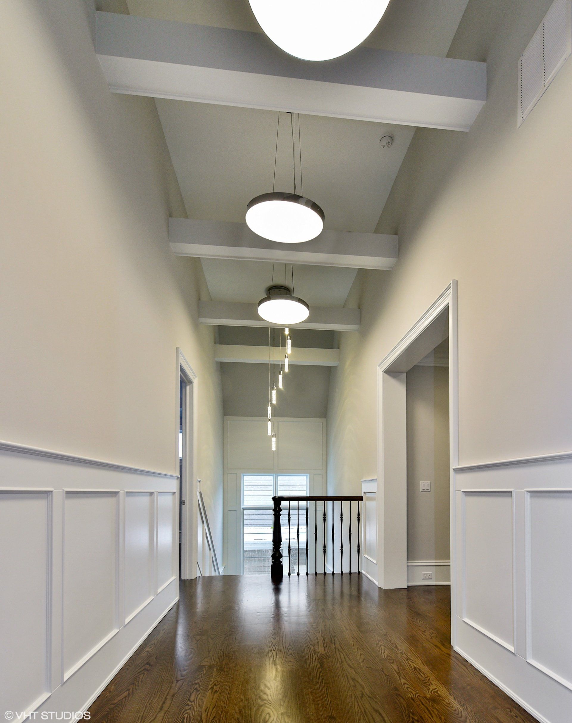 A long hallway with white walls and wooden floors