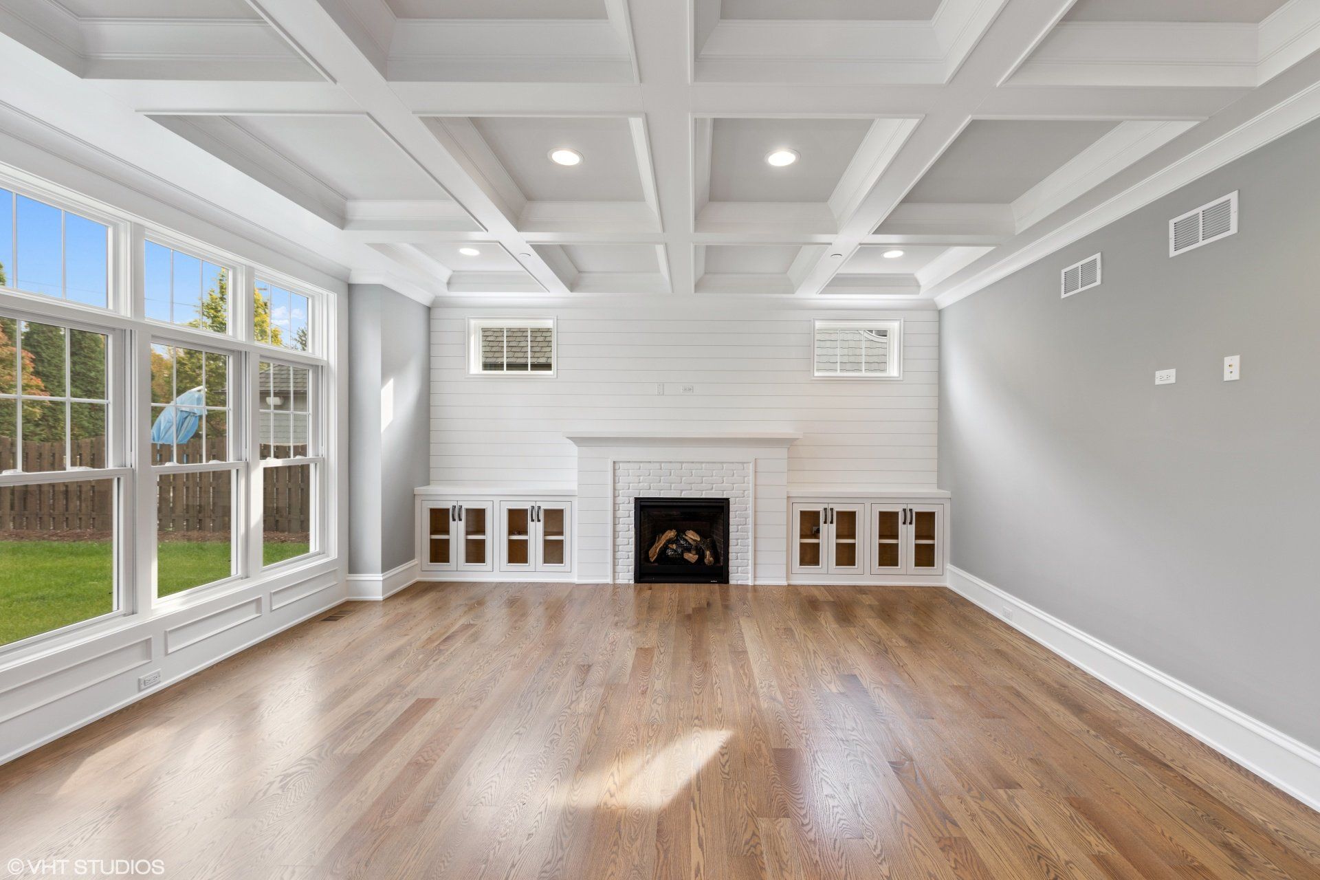 An empty living room with hardwood floors and a fireplace.