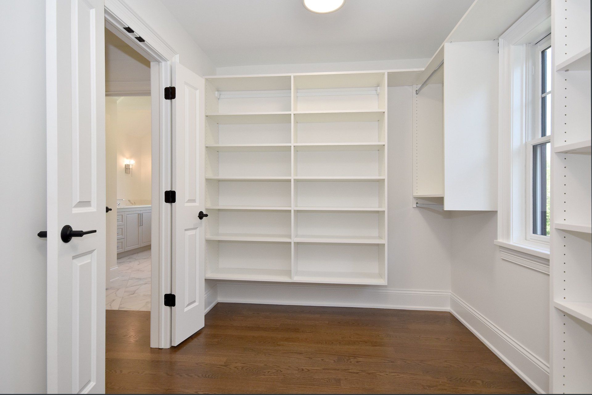 A walk in closet with lots of shelves and a window.