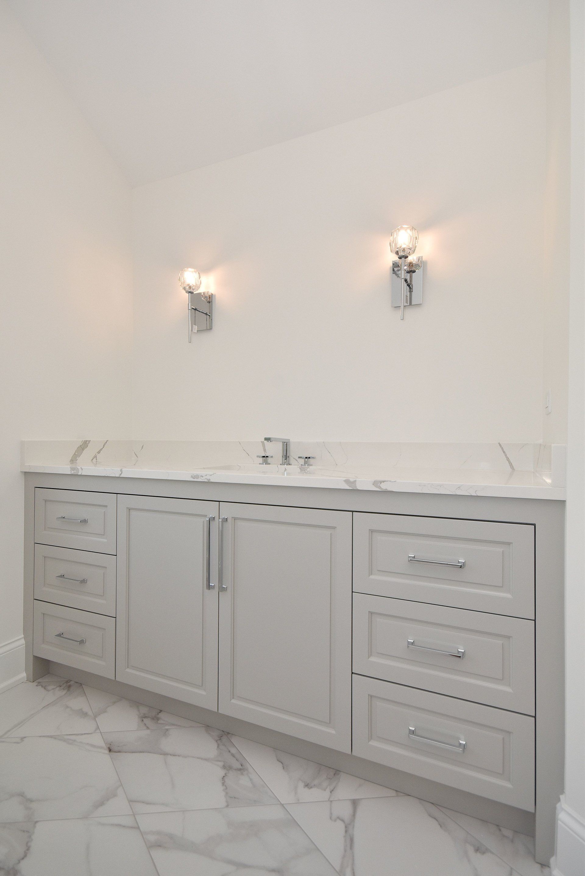 A bathroom with two sinks , drawers , and a marble floor.