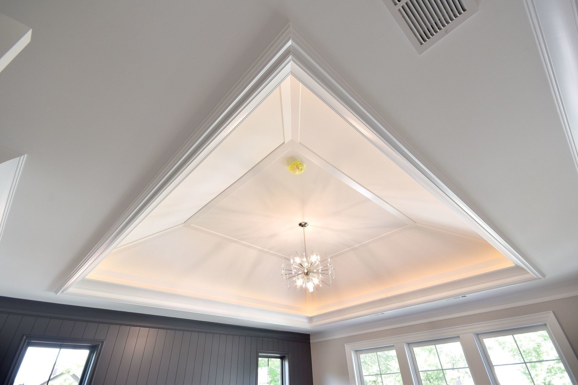 A bedroom with a triangle shaped ceiling and a chandelier