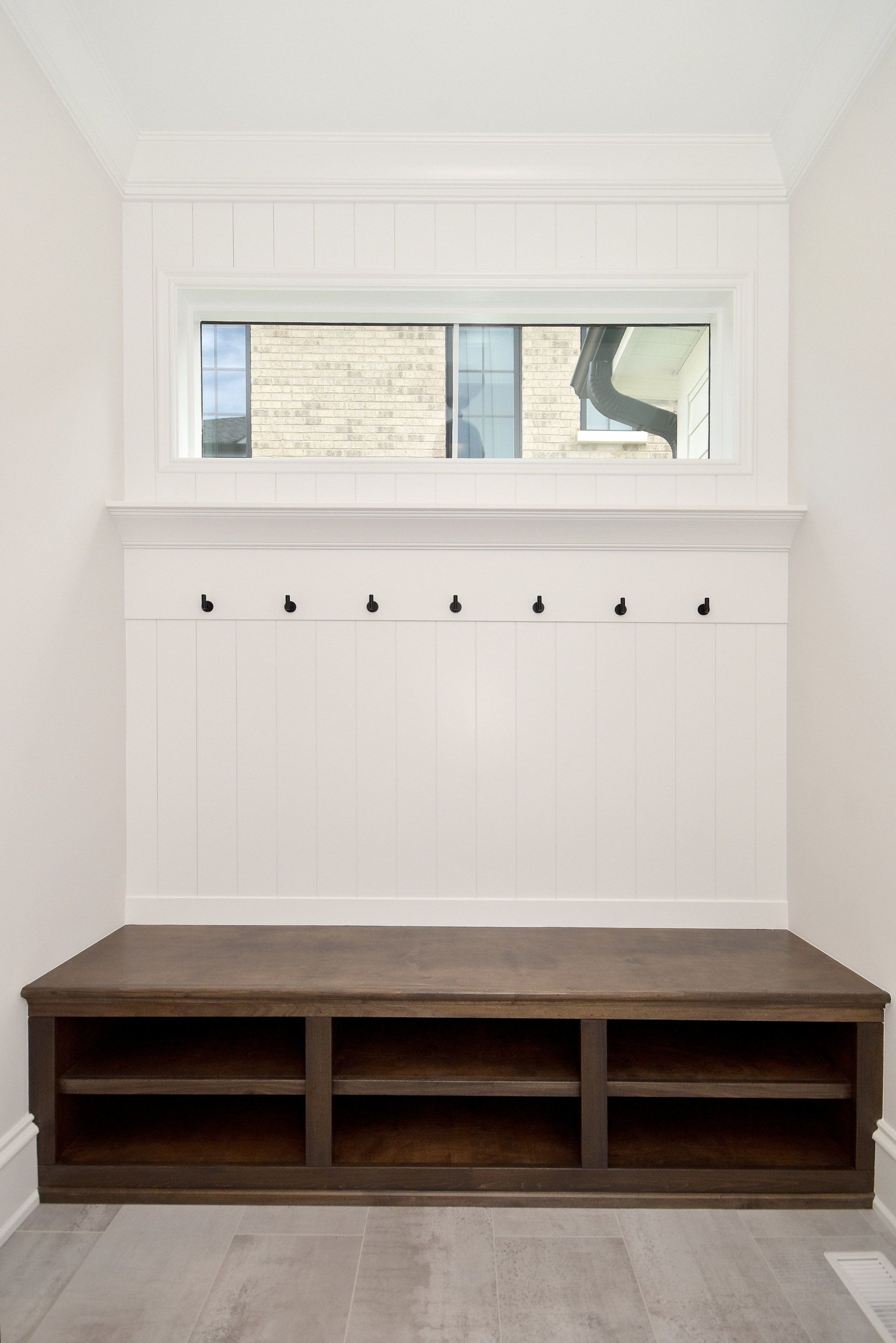 A mud room with a wooden bench and a window.