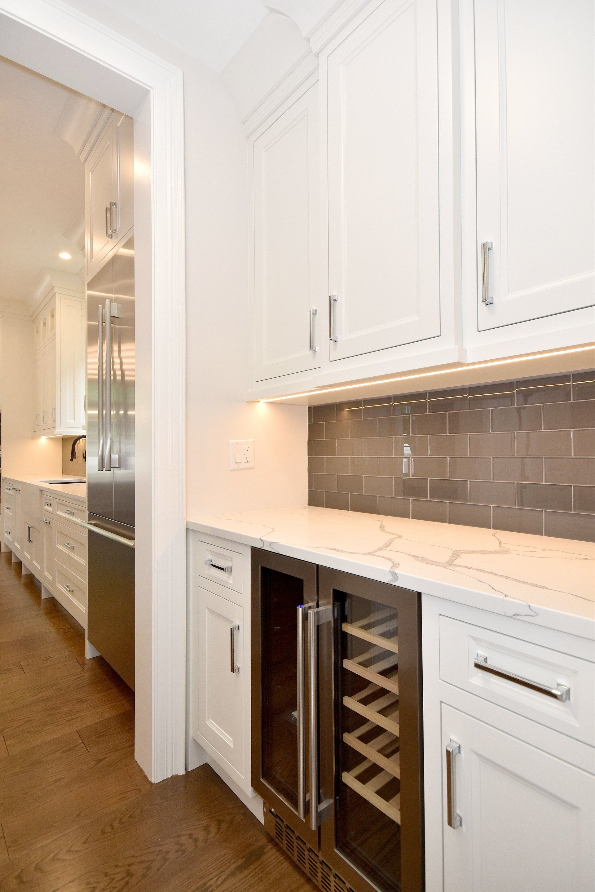 A kitchen with white cabinets and a wine cooler