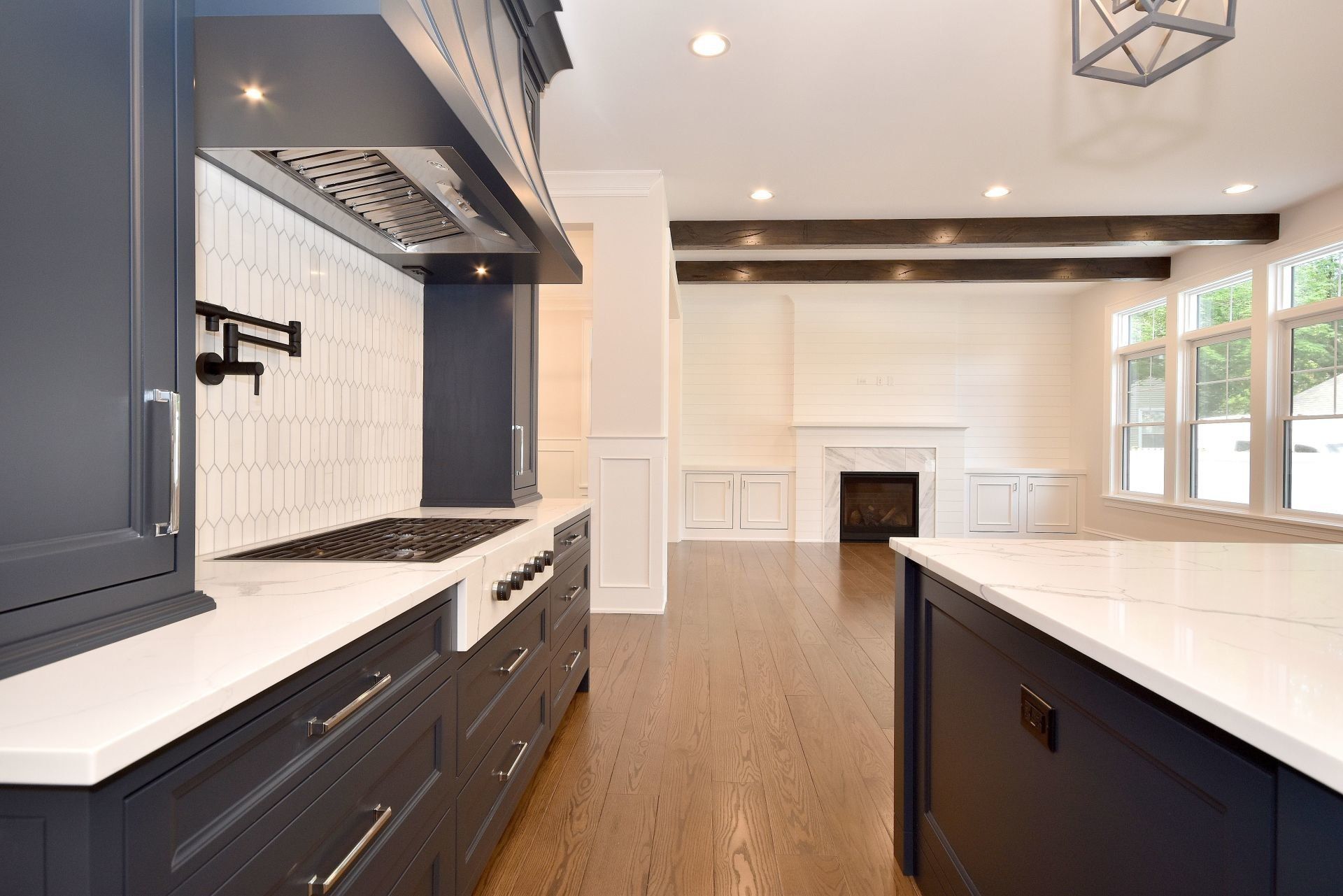 A kitchen with blue cabinets , white counter tops , a stove and a fireplace.