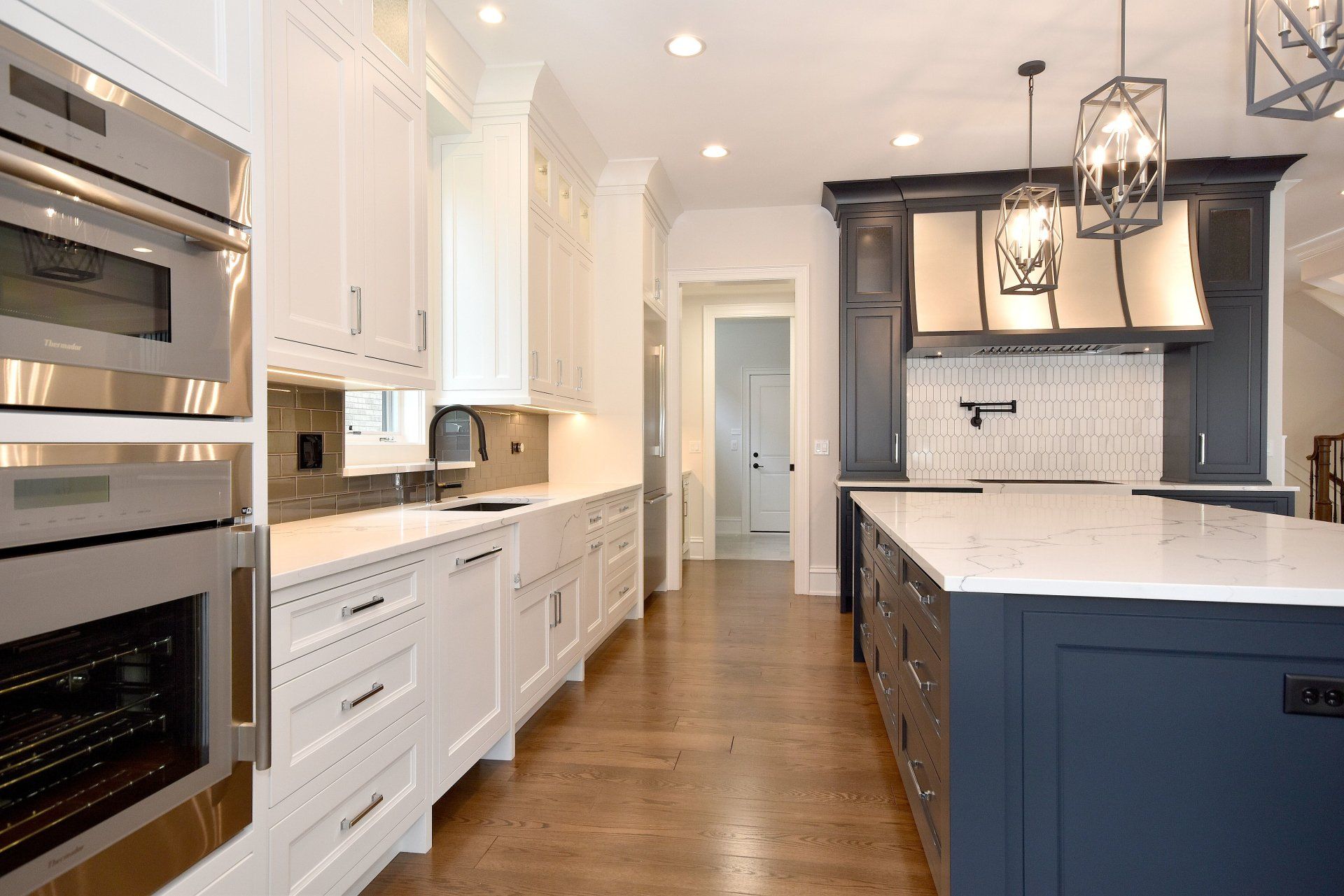 A kitchen with white cabinets , stainless steel appliances , and a large island.