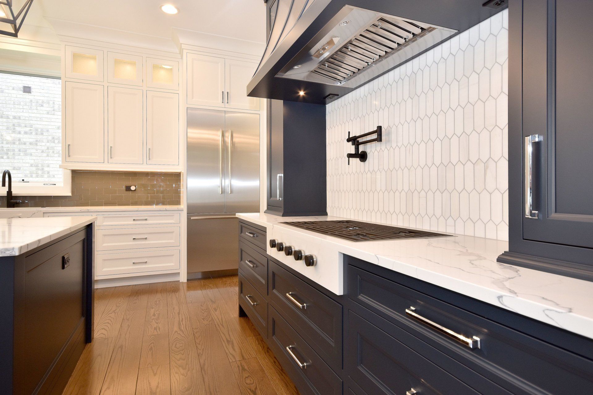 A kitchen with black cabinets and white counter tops and a stove top oven.