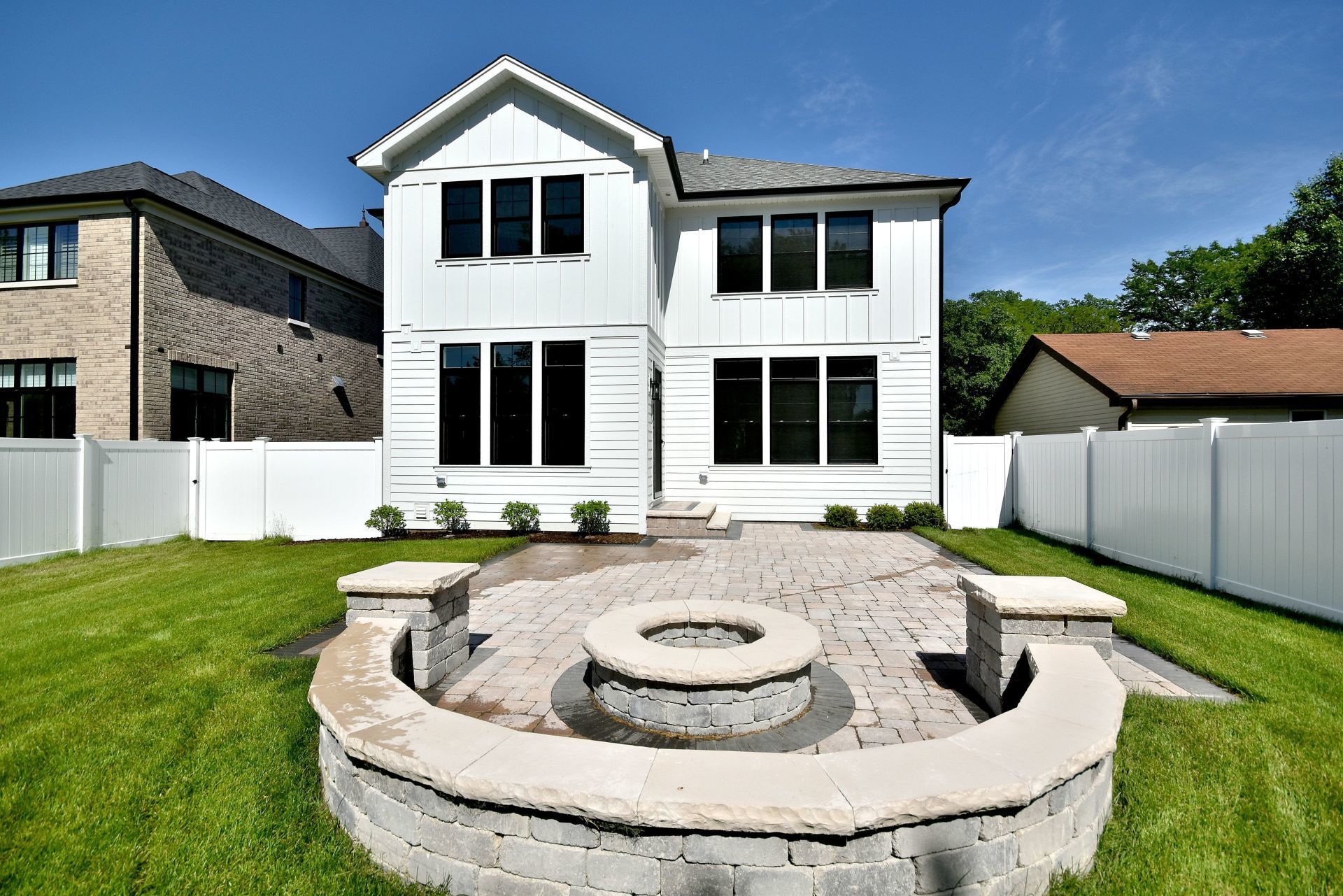 A large white house with a fire pit in the backyard.