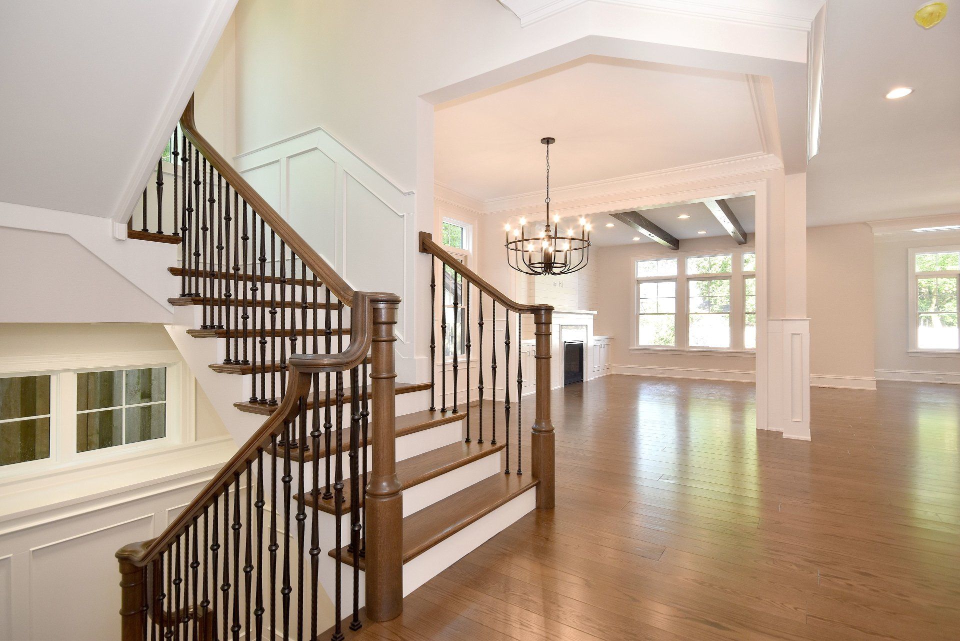 A staircase in an empty house with a chandelier hanging from the ceiling.