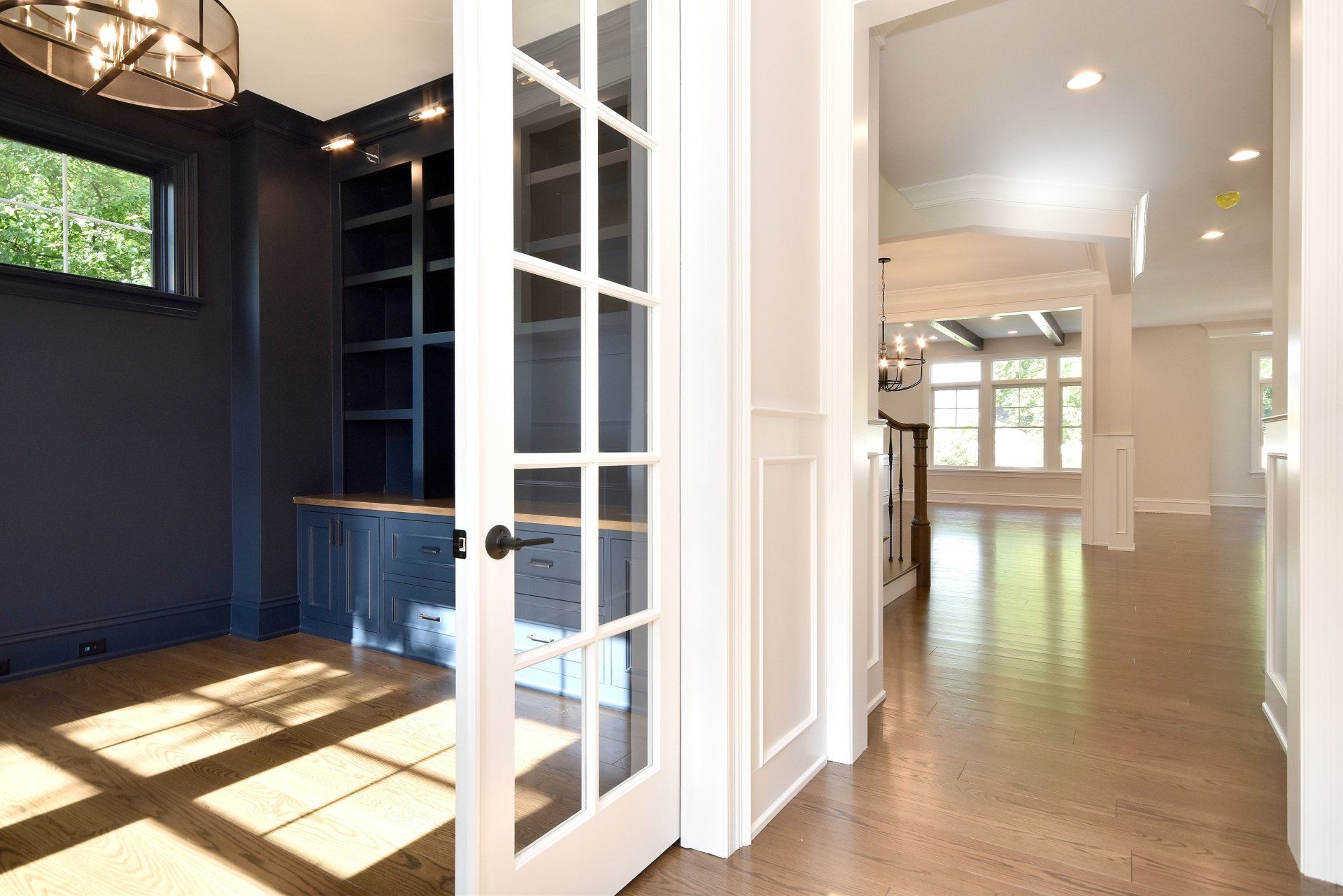 A hallway in a house with french doors leading to a dining room.