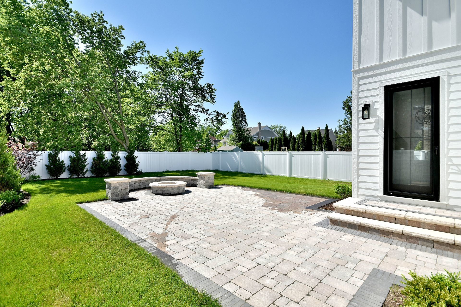 A white house with a patio and a fire pit in the backyard.