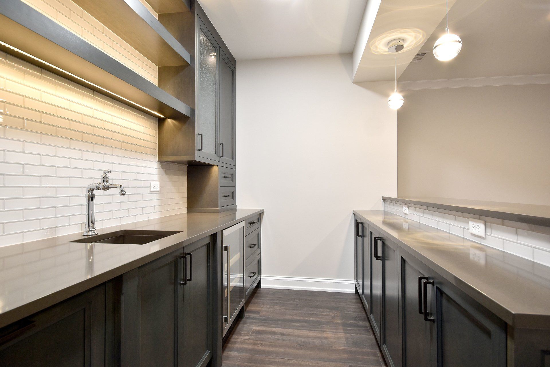 A kitchen with gray cabinets , granite counter tops , and a sink.