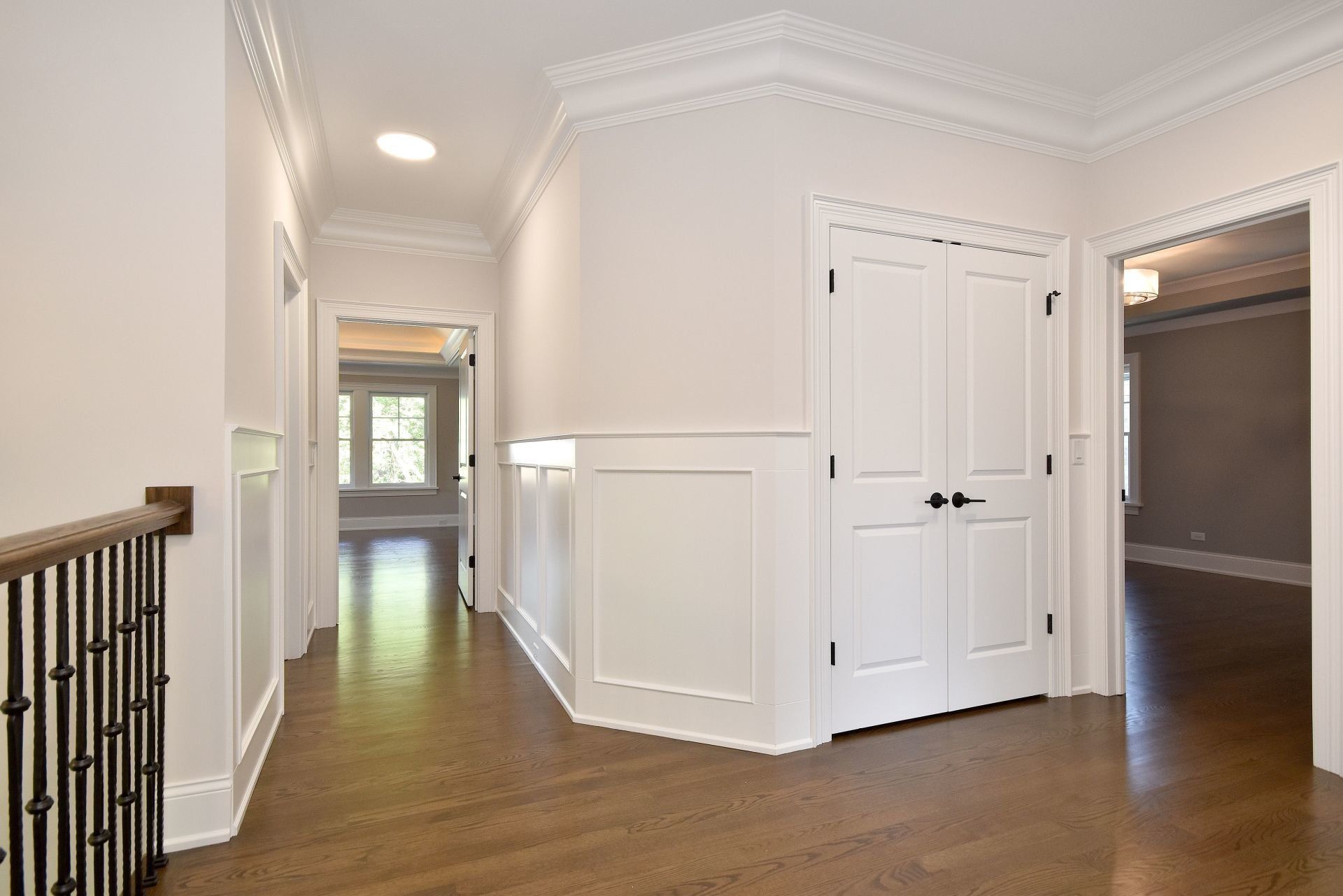 An empty hallway with white walls and hardwood floors in a house.