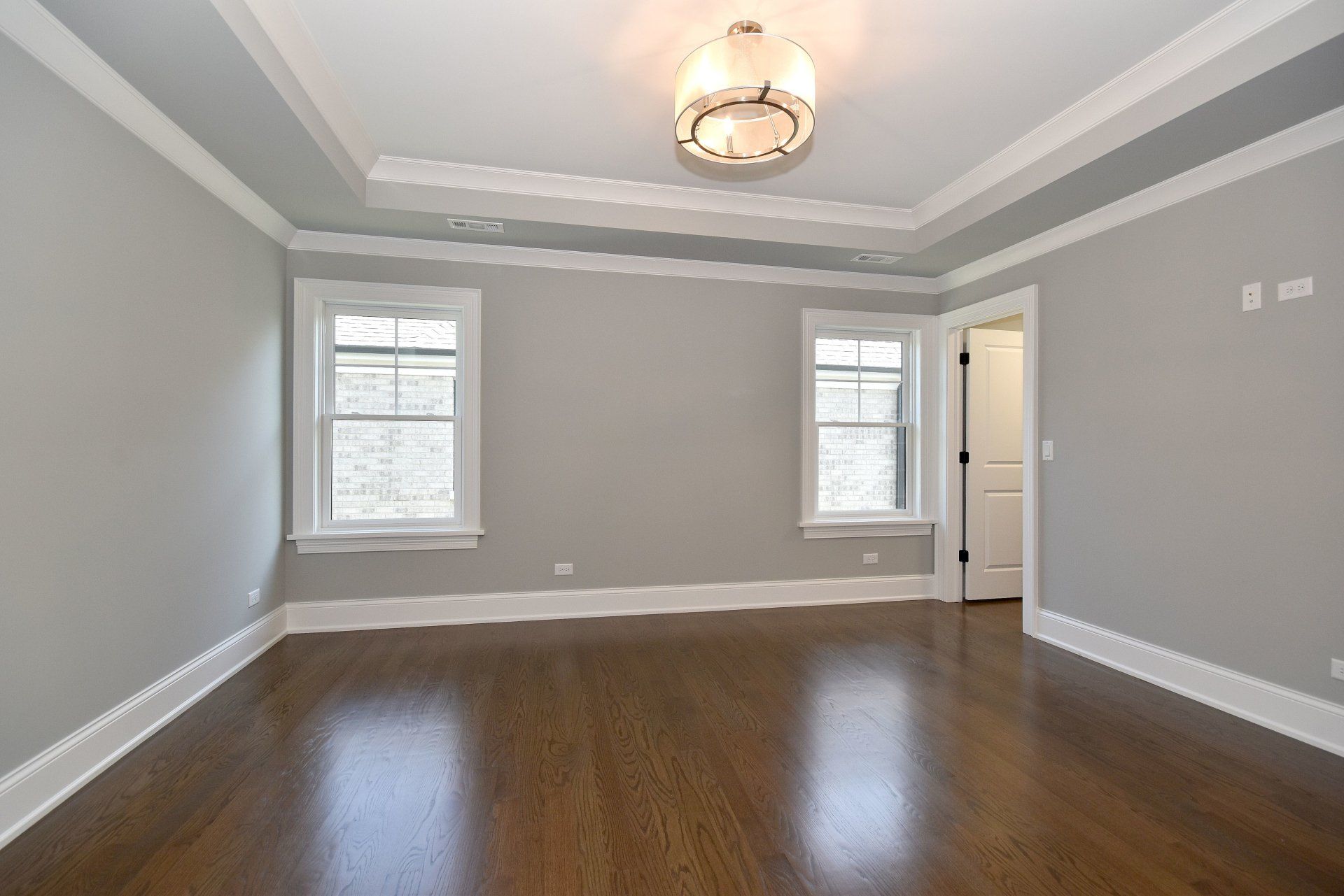 An empty room with hardwood floors and gray walls