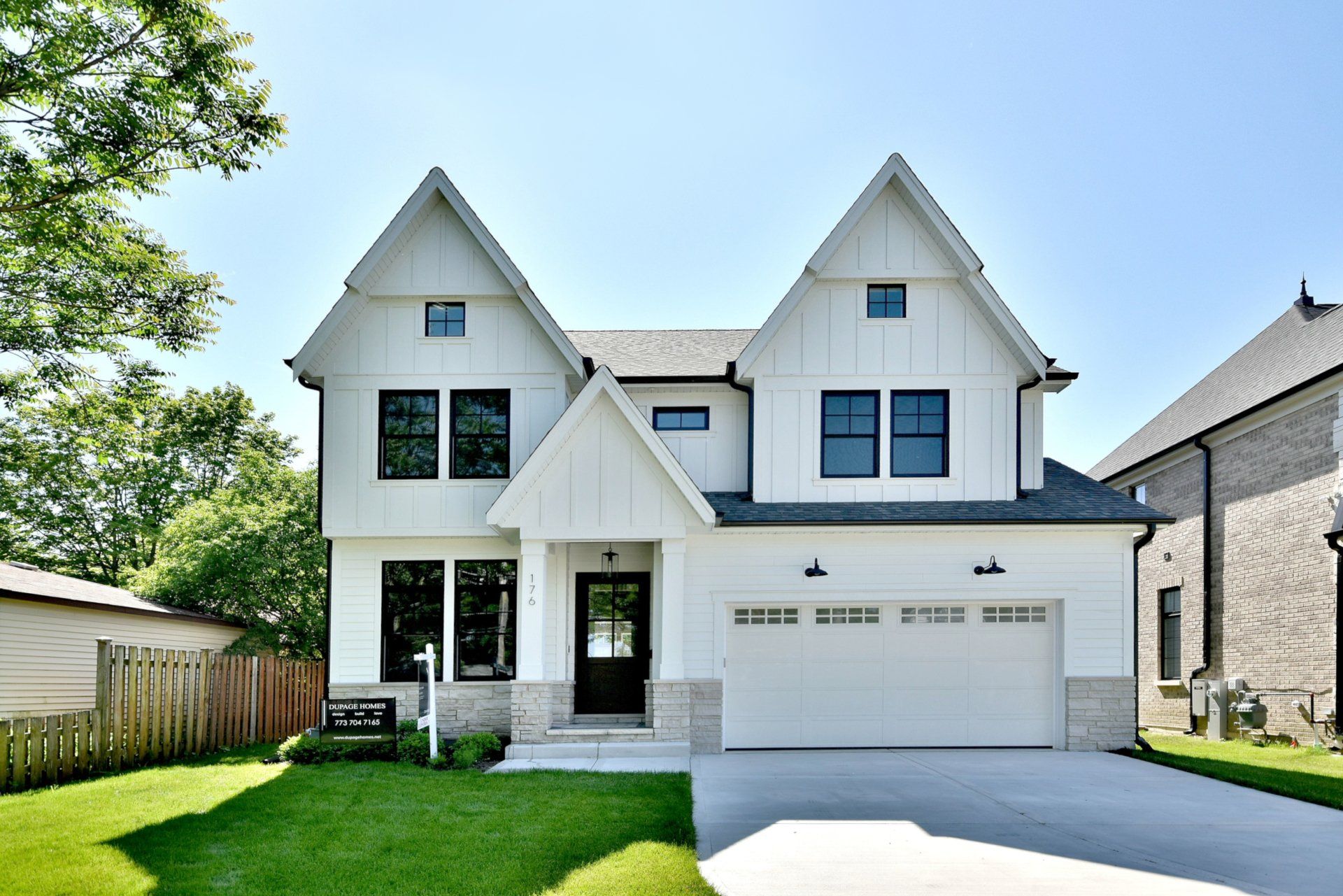 A white house with black windows and a white garage door.
