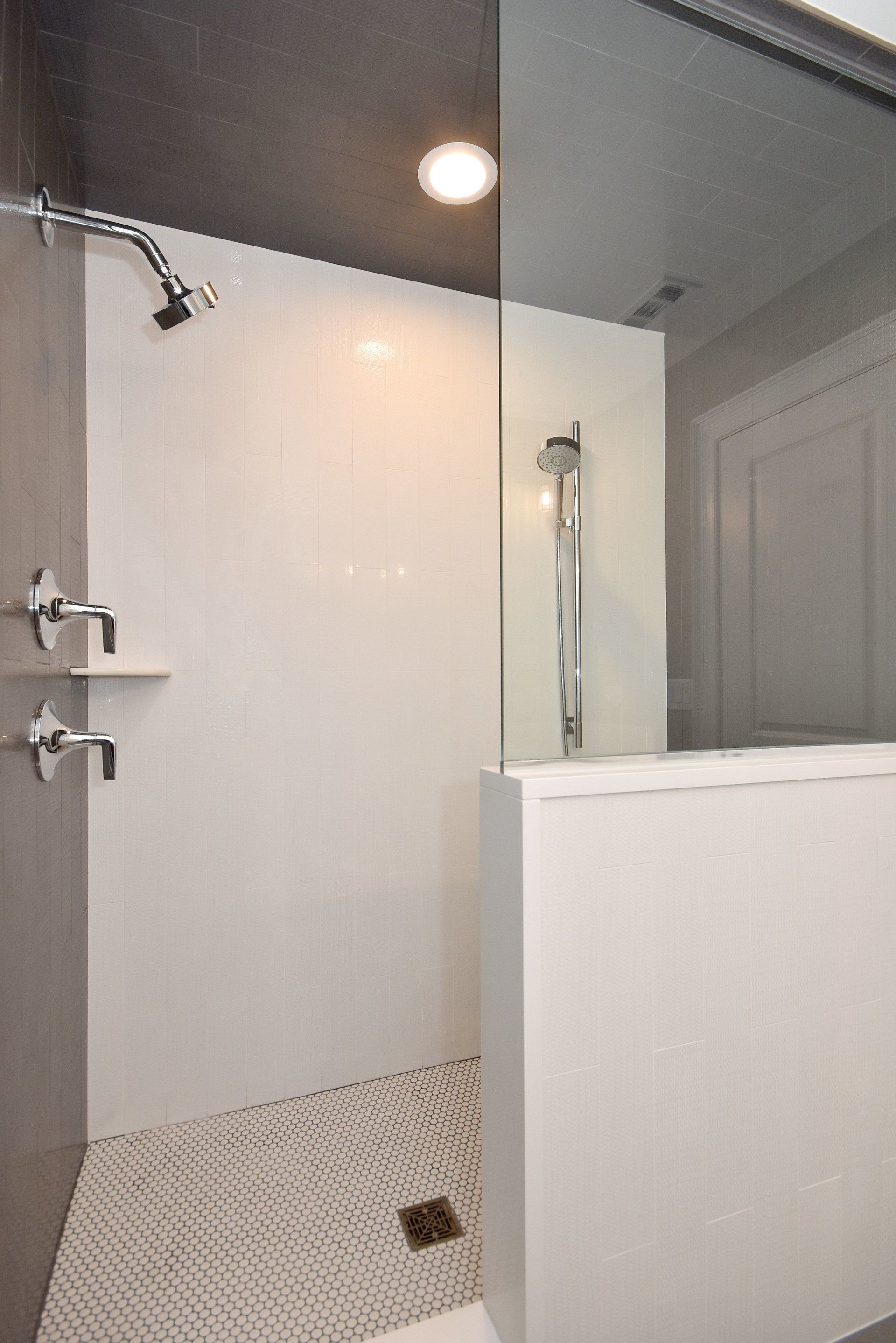 A bathroom with a walk in shower and a glass door