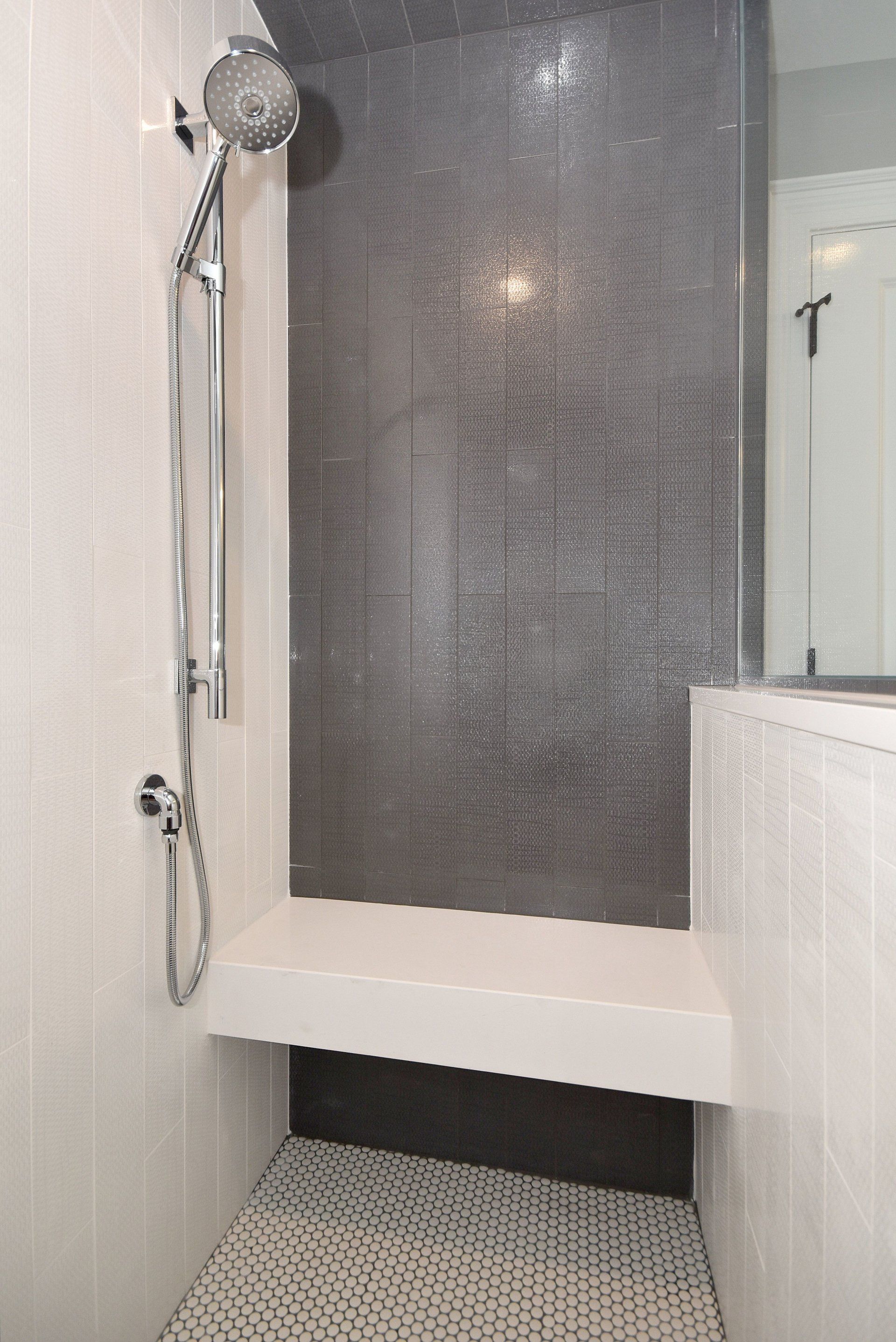 A shower with a bench and a shower head in a bathroom.
