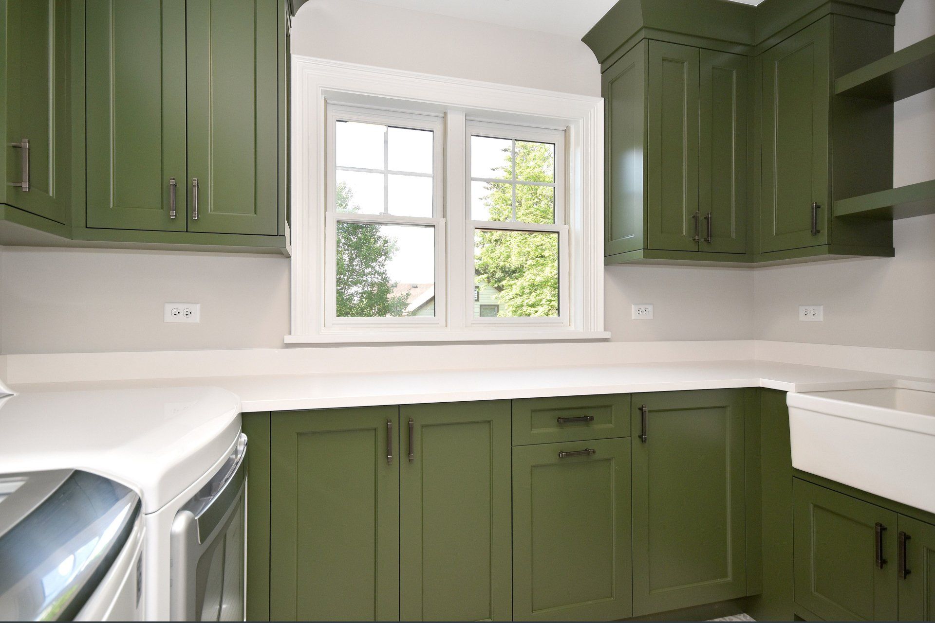 A kitchen with green cabinets and white counter tops