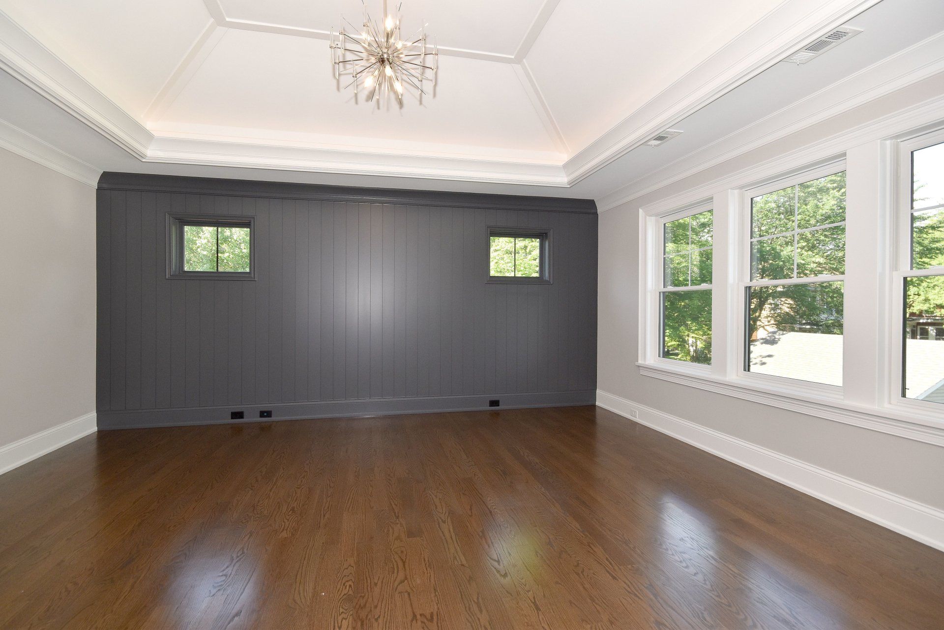An empty room with hardwood floors and a chandelier