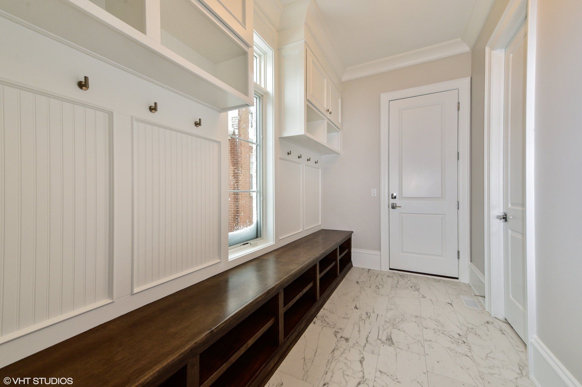 A hallway with a bench and a window in a house.