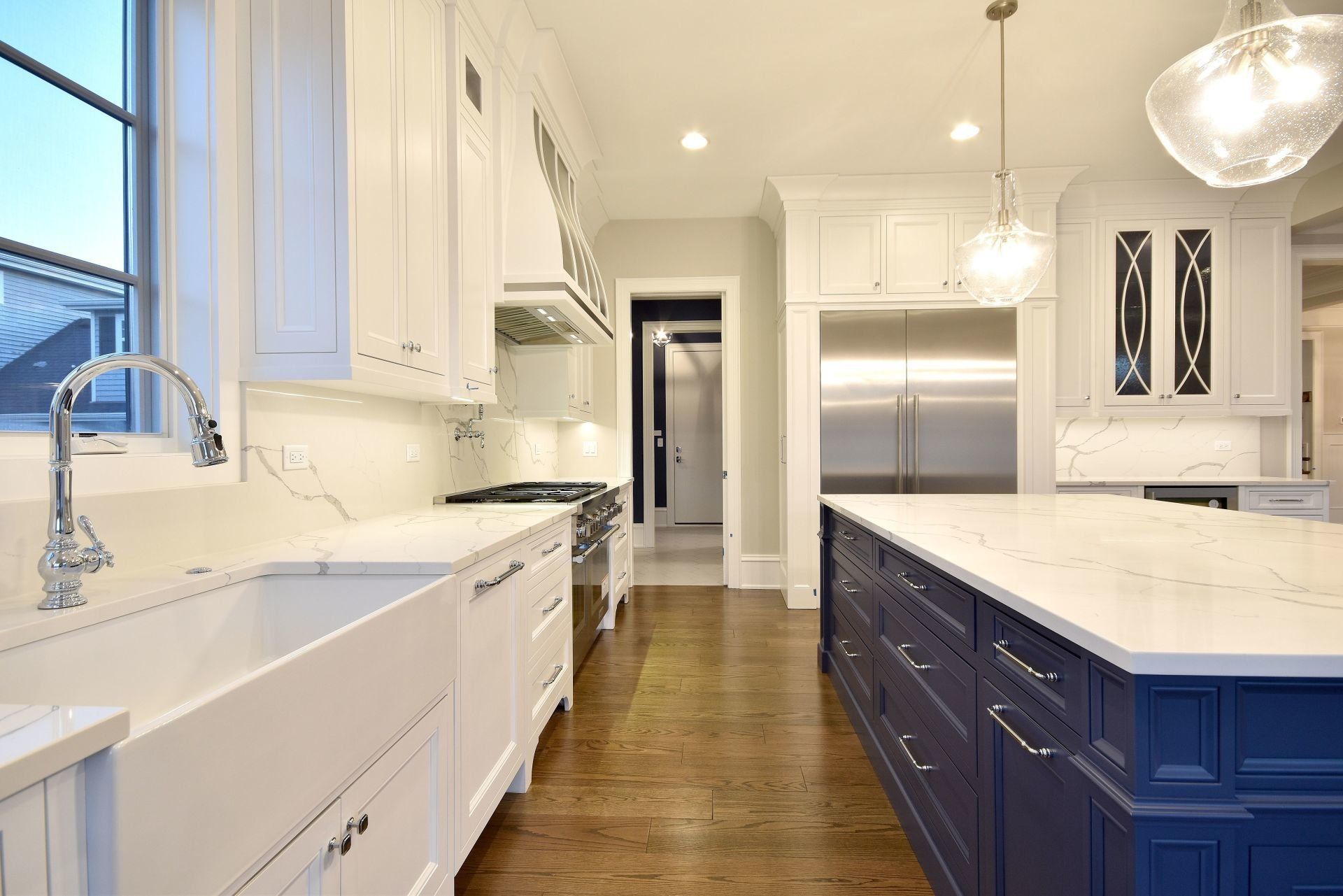 A kitchen with white cabinets and blue cabinets and a large island.