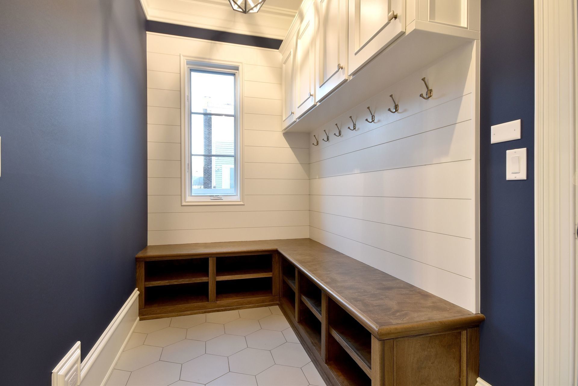 A mud room with a bench and hooks on the wall.