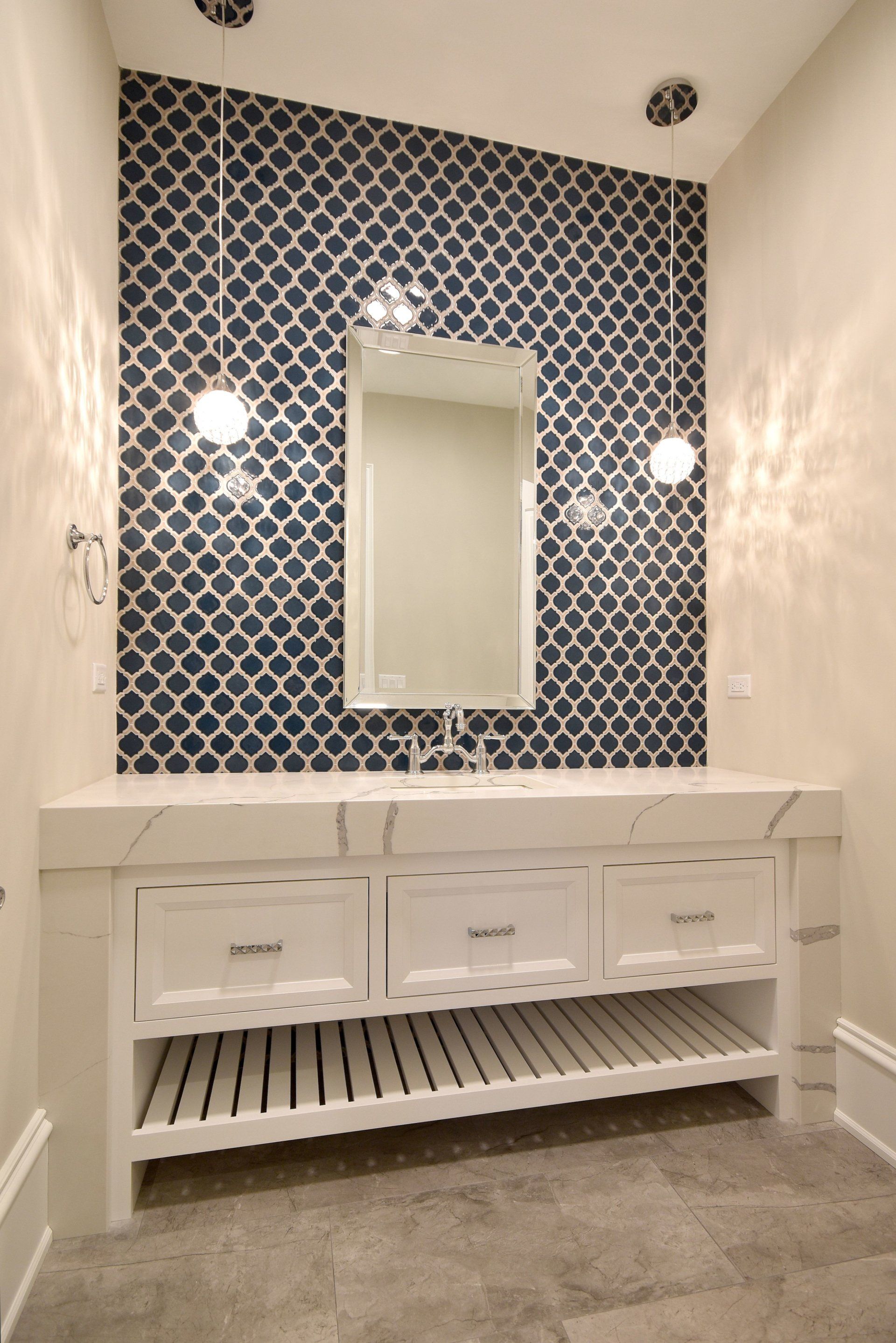 A bathroom with a sink , mirror and blue tiles on the wall.