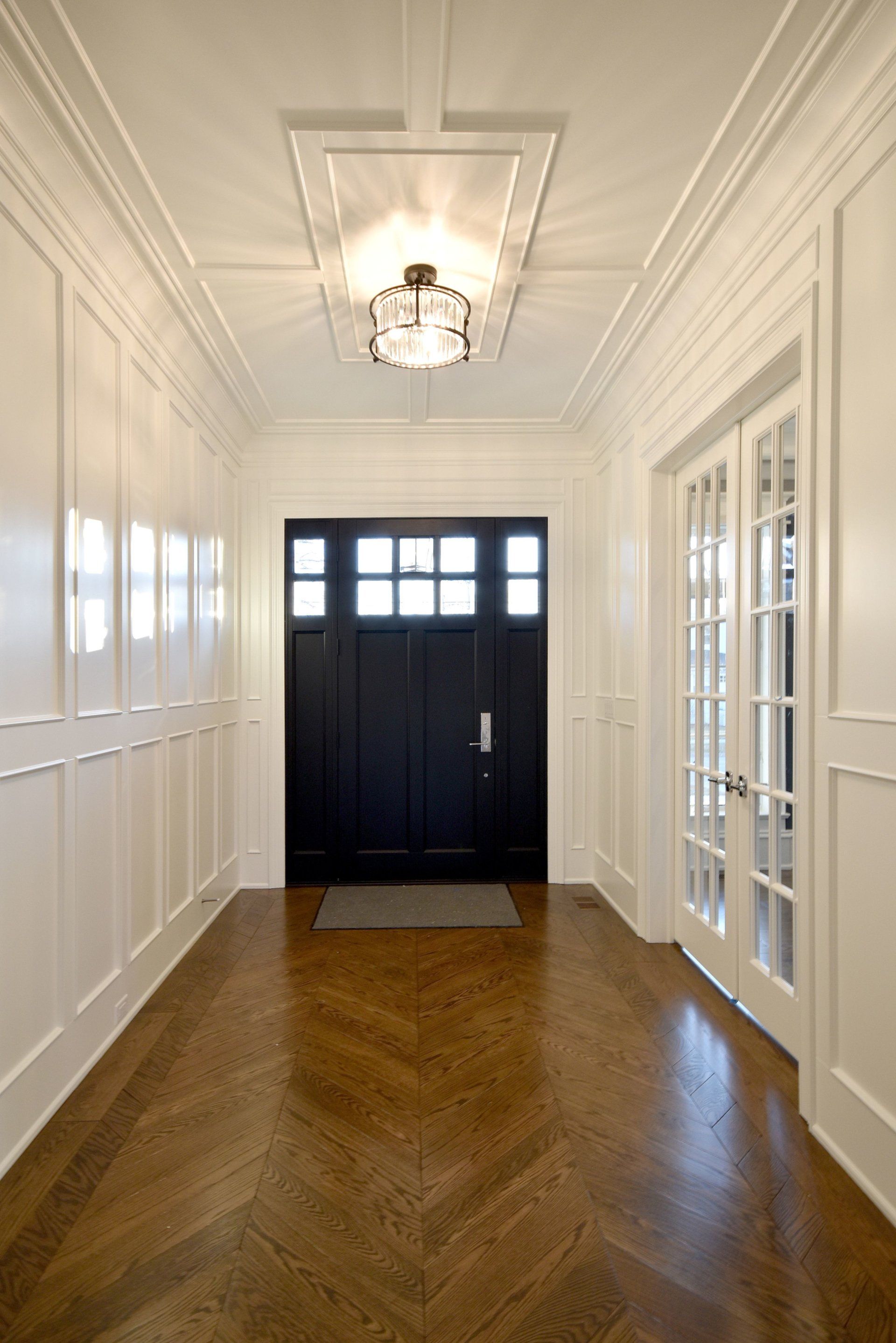A hallway with a black door and a light on the ceiling