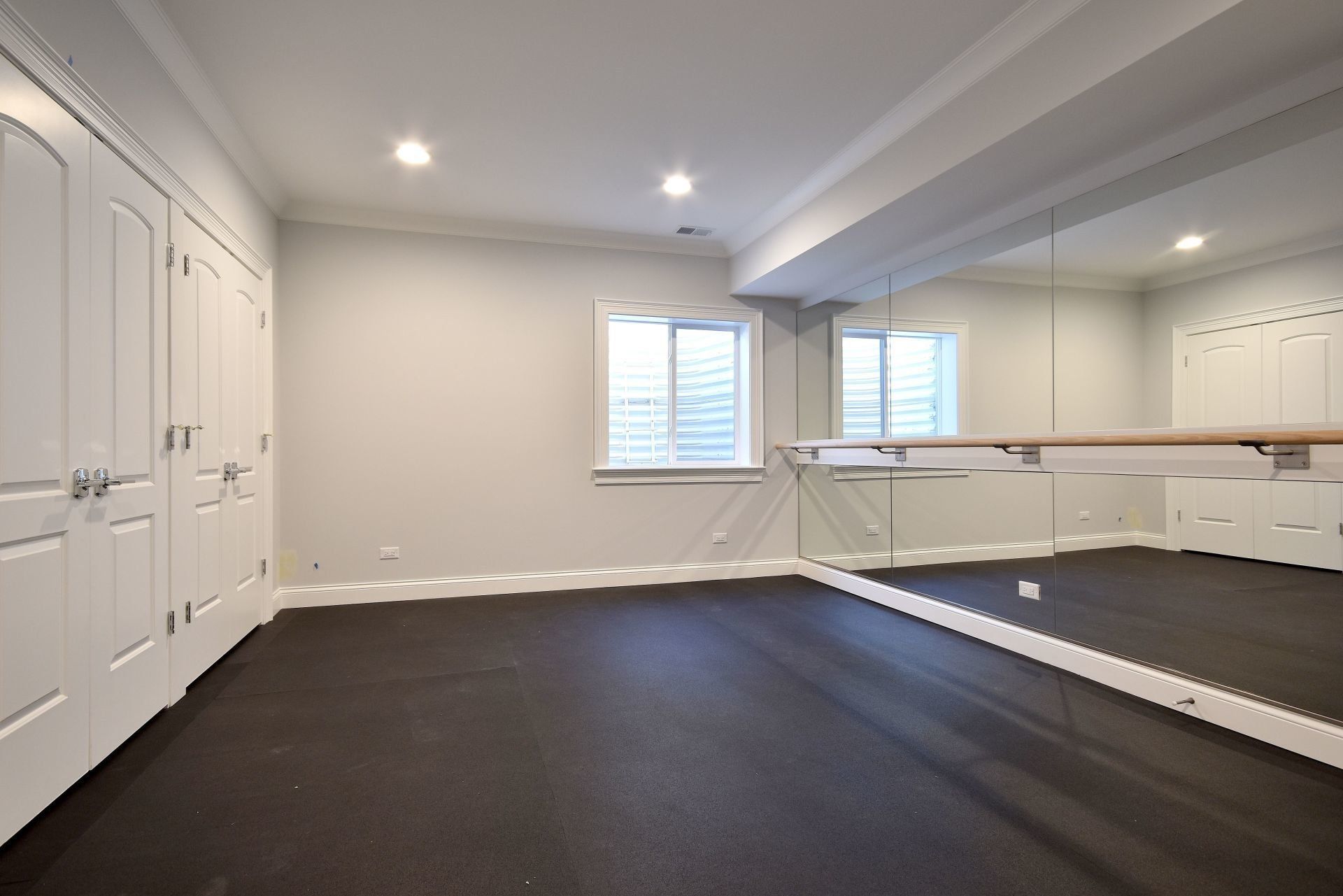 An empty room with a large mirror and a ballet barre