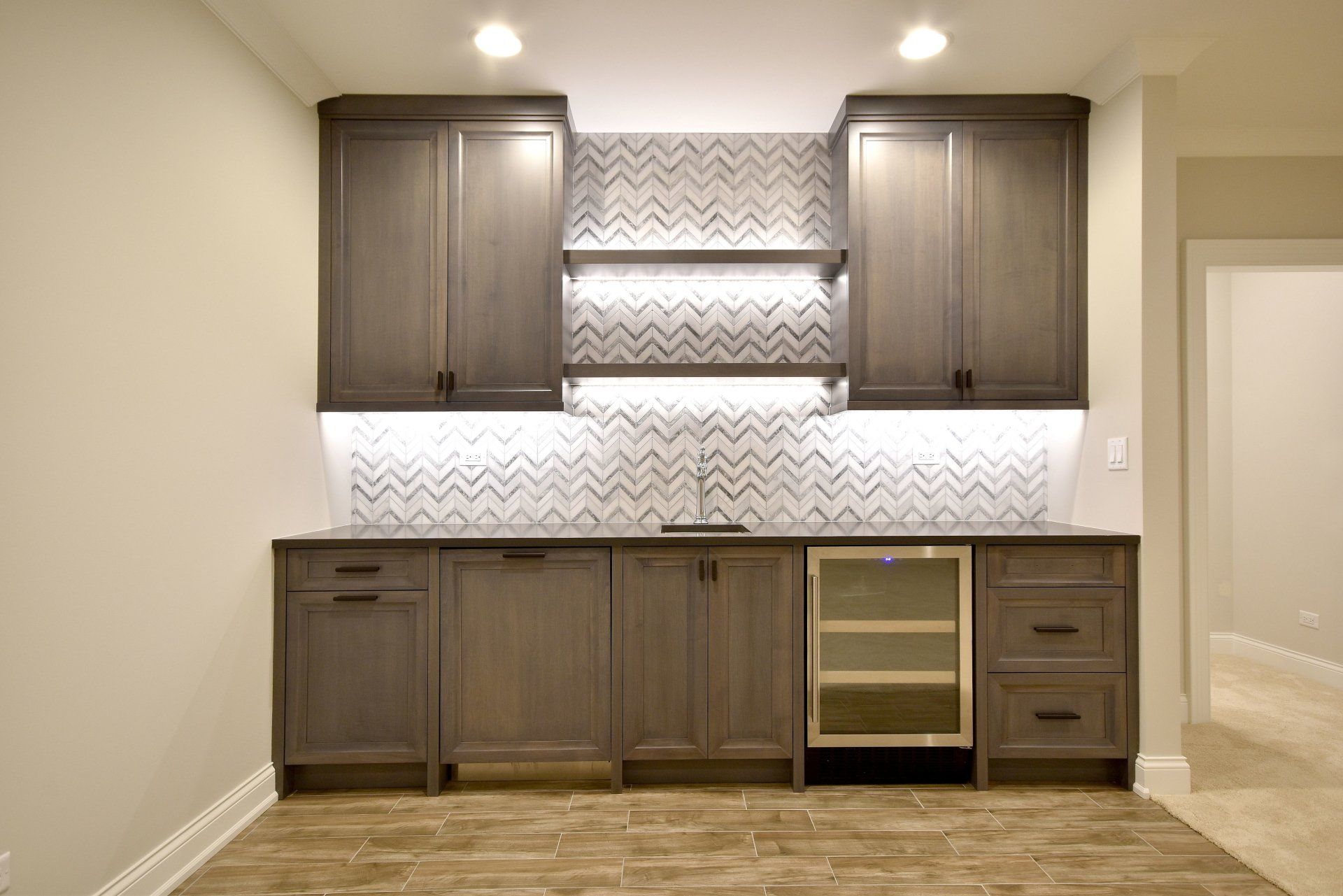 A kitchen with gray cabinets , a sink , and a refrigerator.
