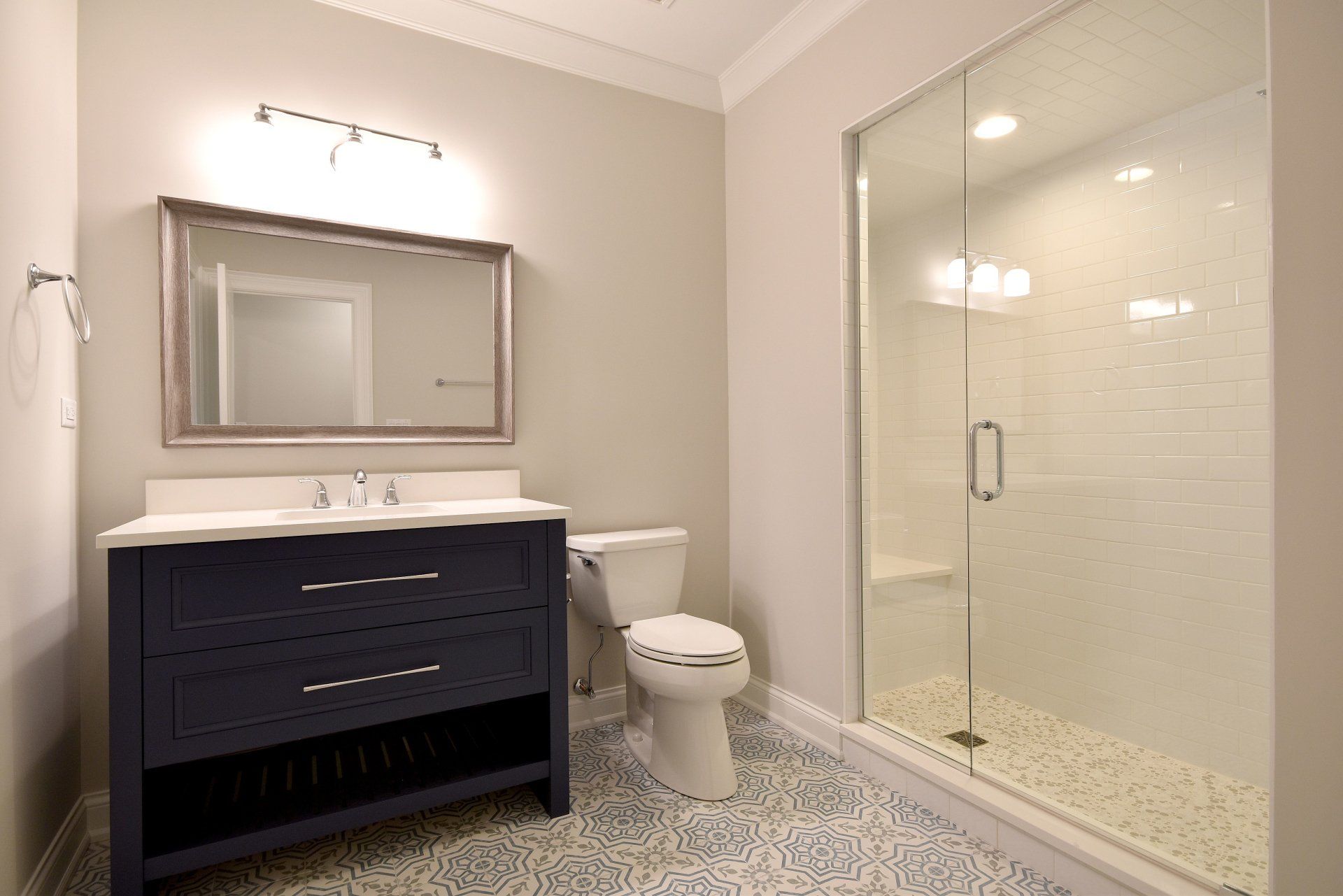 A bathroom with a toilet , sink , mirror and walk in shower.