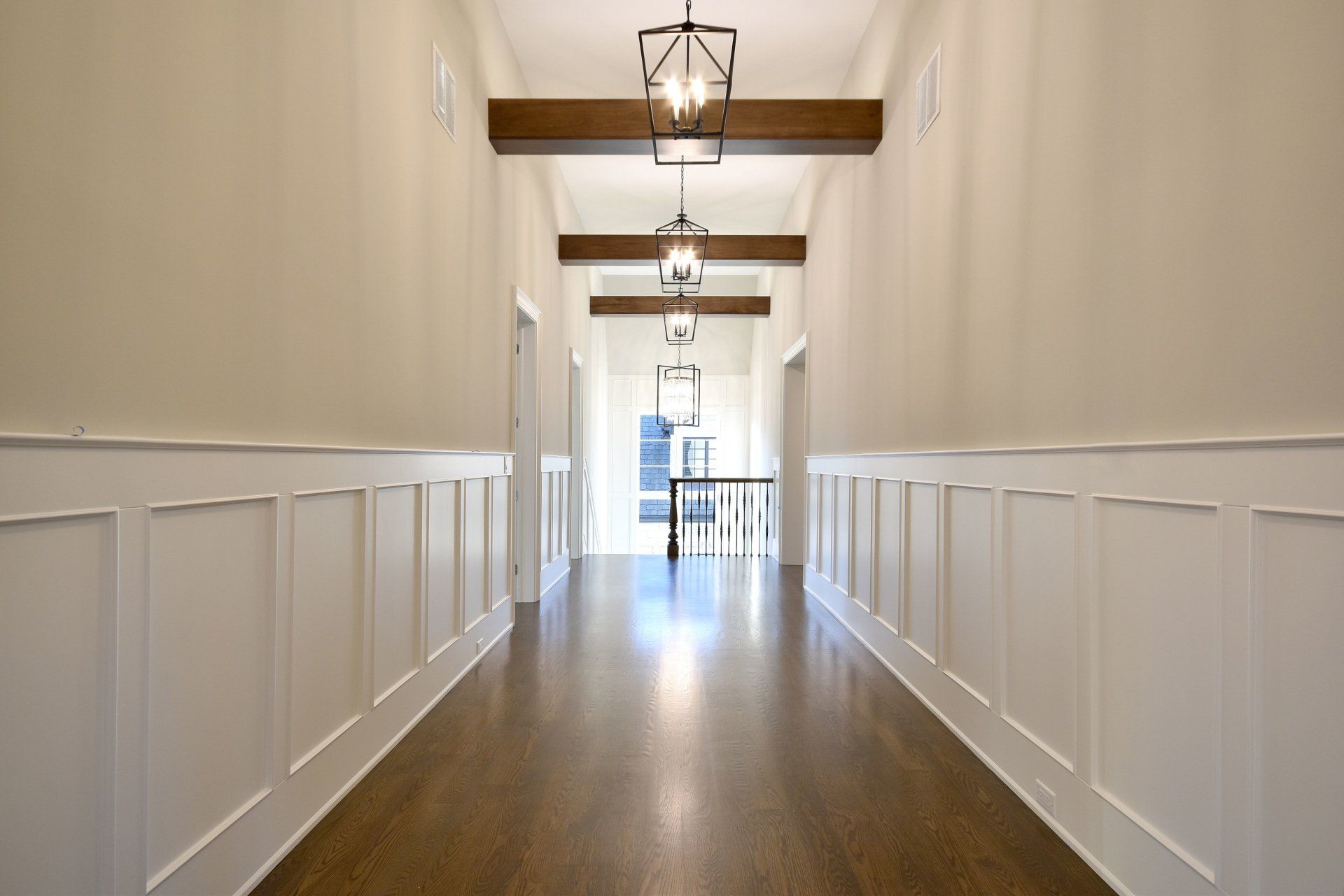 A long hallway with white walls and wooden floors in a house.