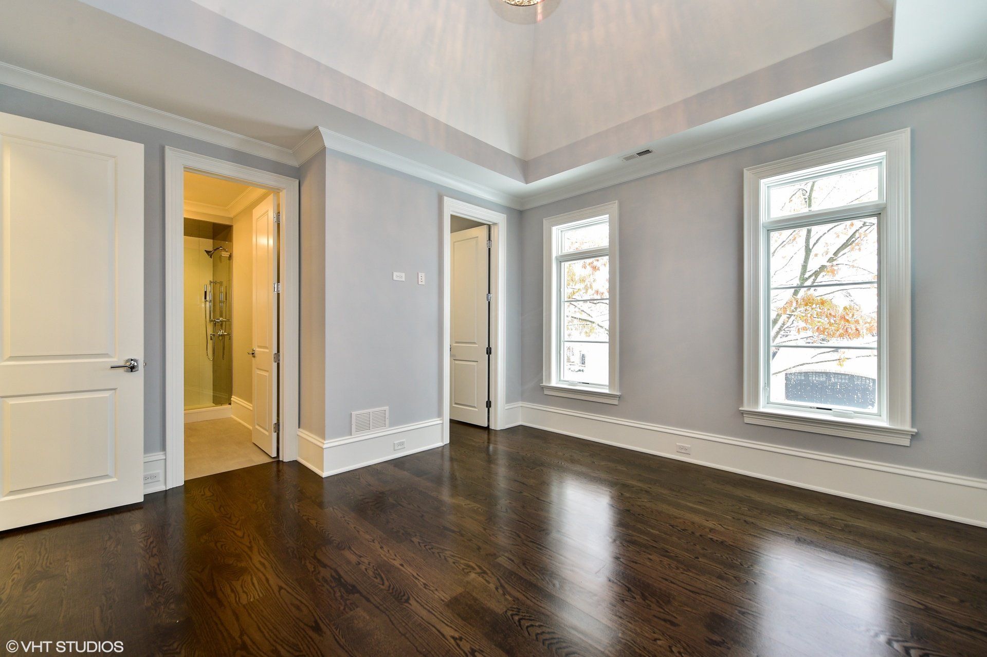 An empty bedroom with hardwood floors and a vaulted ceiling.