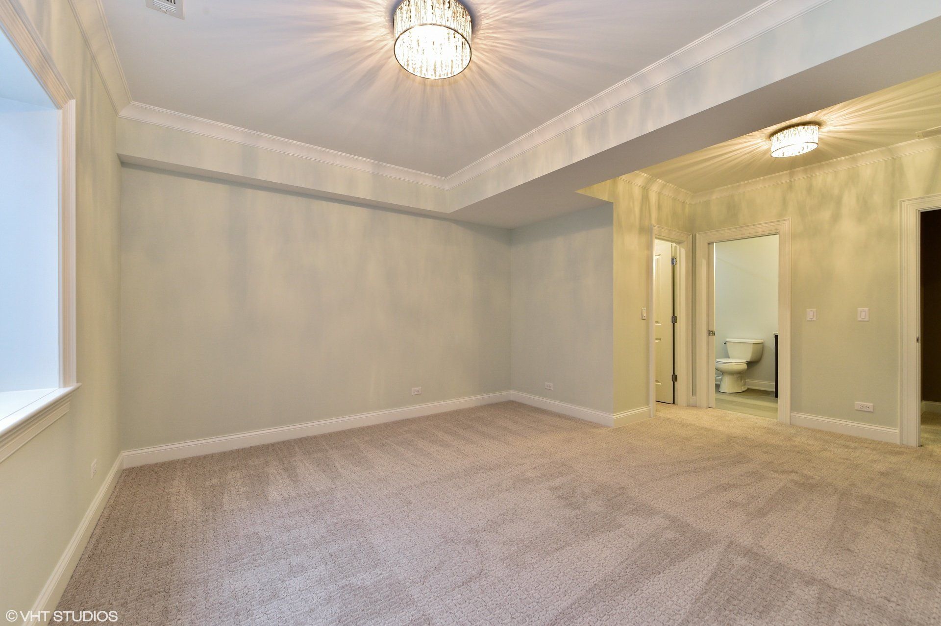 An empty room with a carpeted floor and a window.