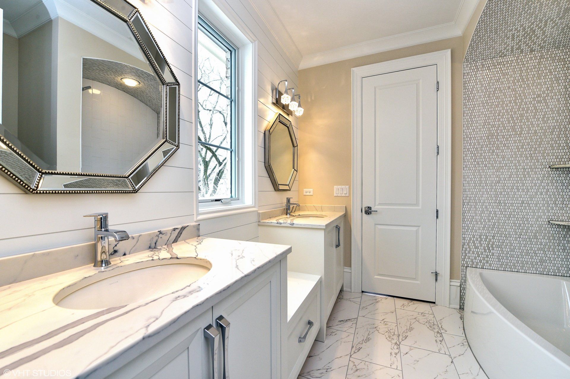 A bathroom with a sink , mirror , tub and window.
