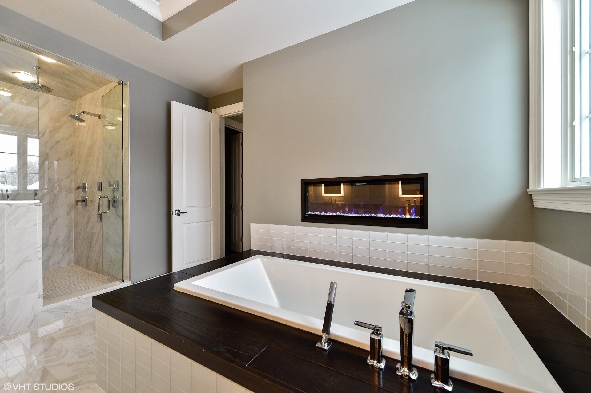 A bathroom with a large bathtub and a fireplace.